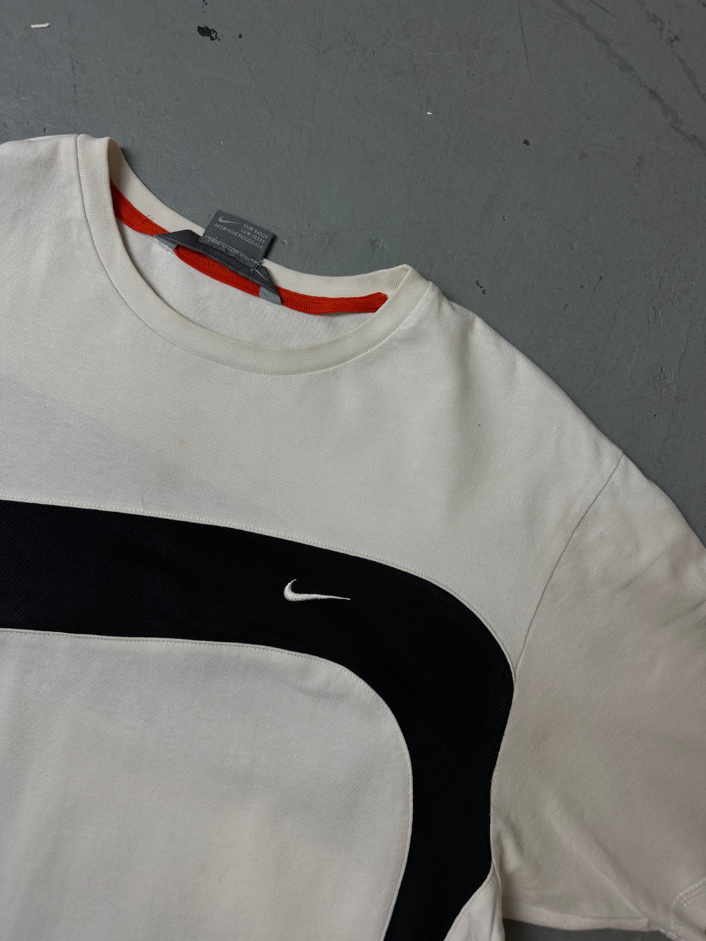 Detailliertes Produktbild von schwarz weißem Nike Tshirt auf grauem Boden 