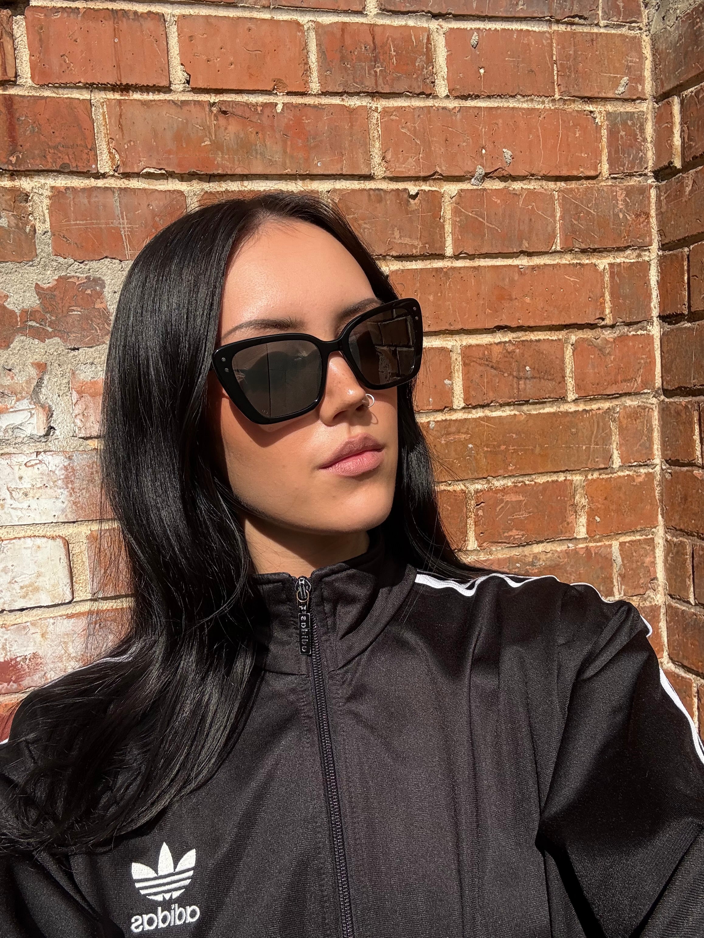 Eine schwarze Sonnenbrille von Dior mit dünnen Bügeln und die Gläser im cateye look 