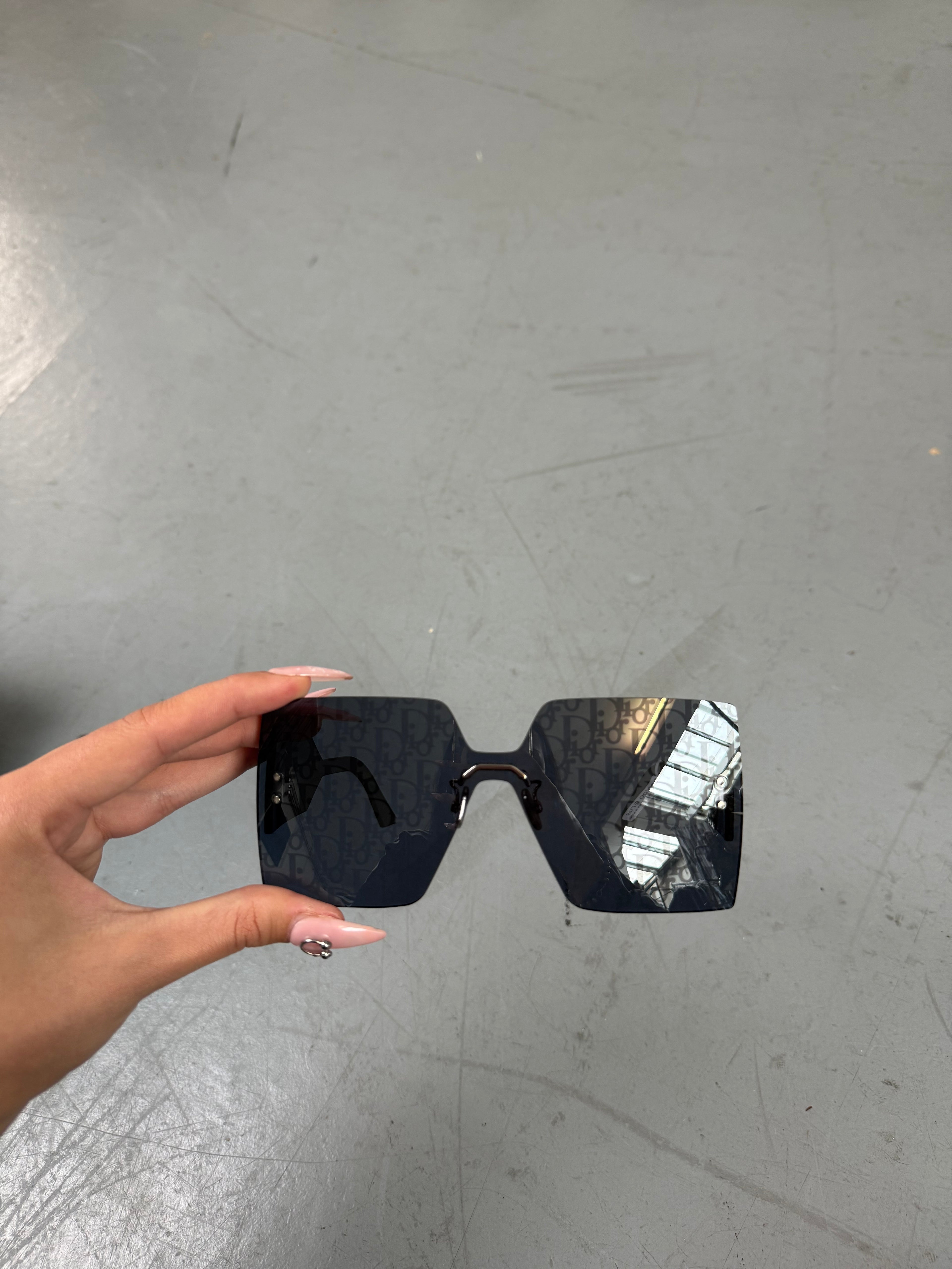Eine neue Sonnenbrille von dir mit großen eckigen Gläsern mit dem Dior monogram drauf 
