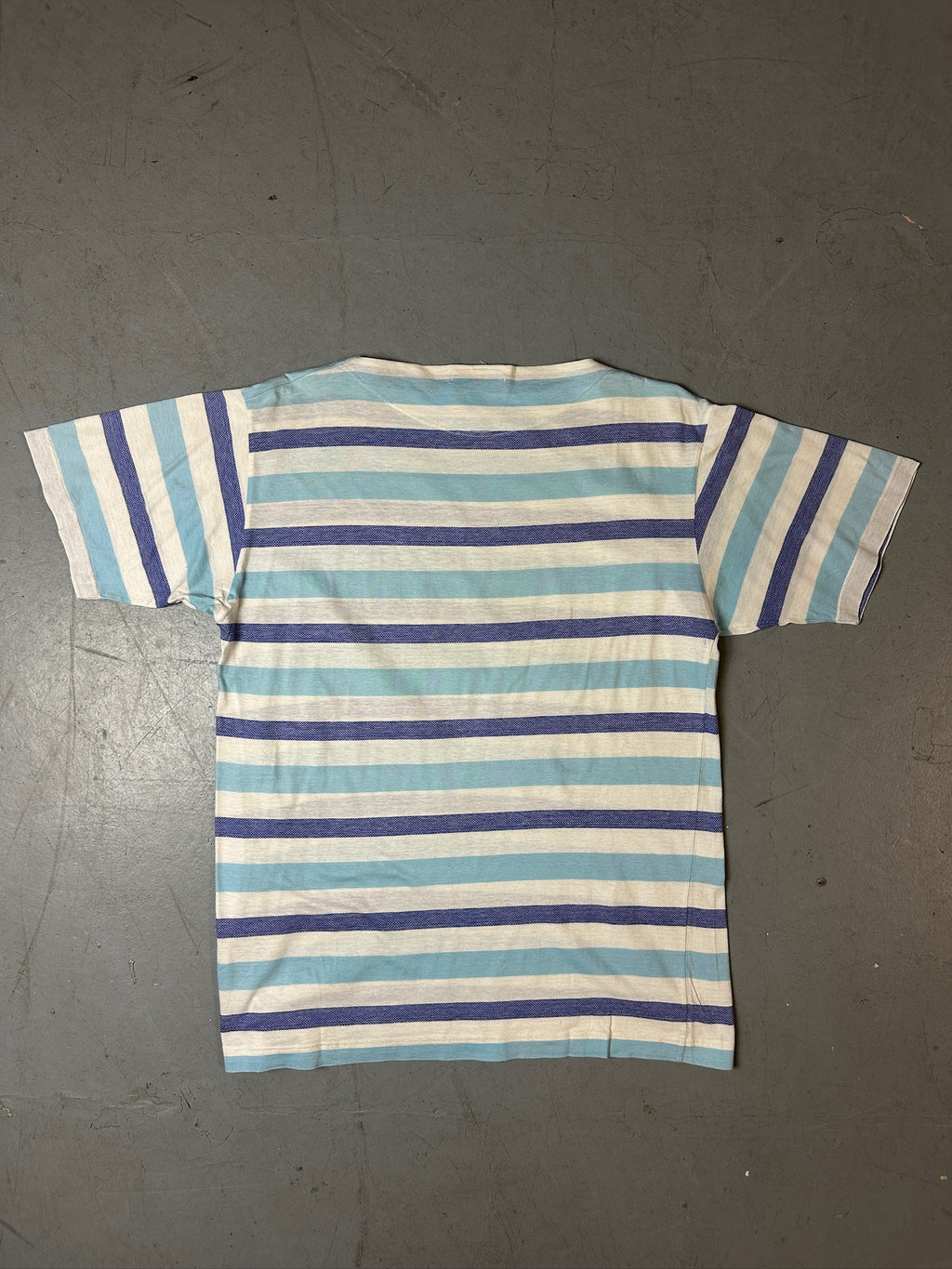 Produktbild von blau weis gestreiftem Stone Island Tshirt auf grauem Boden 