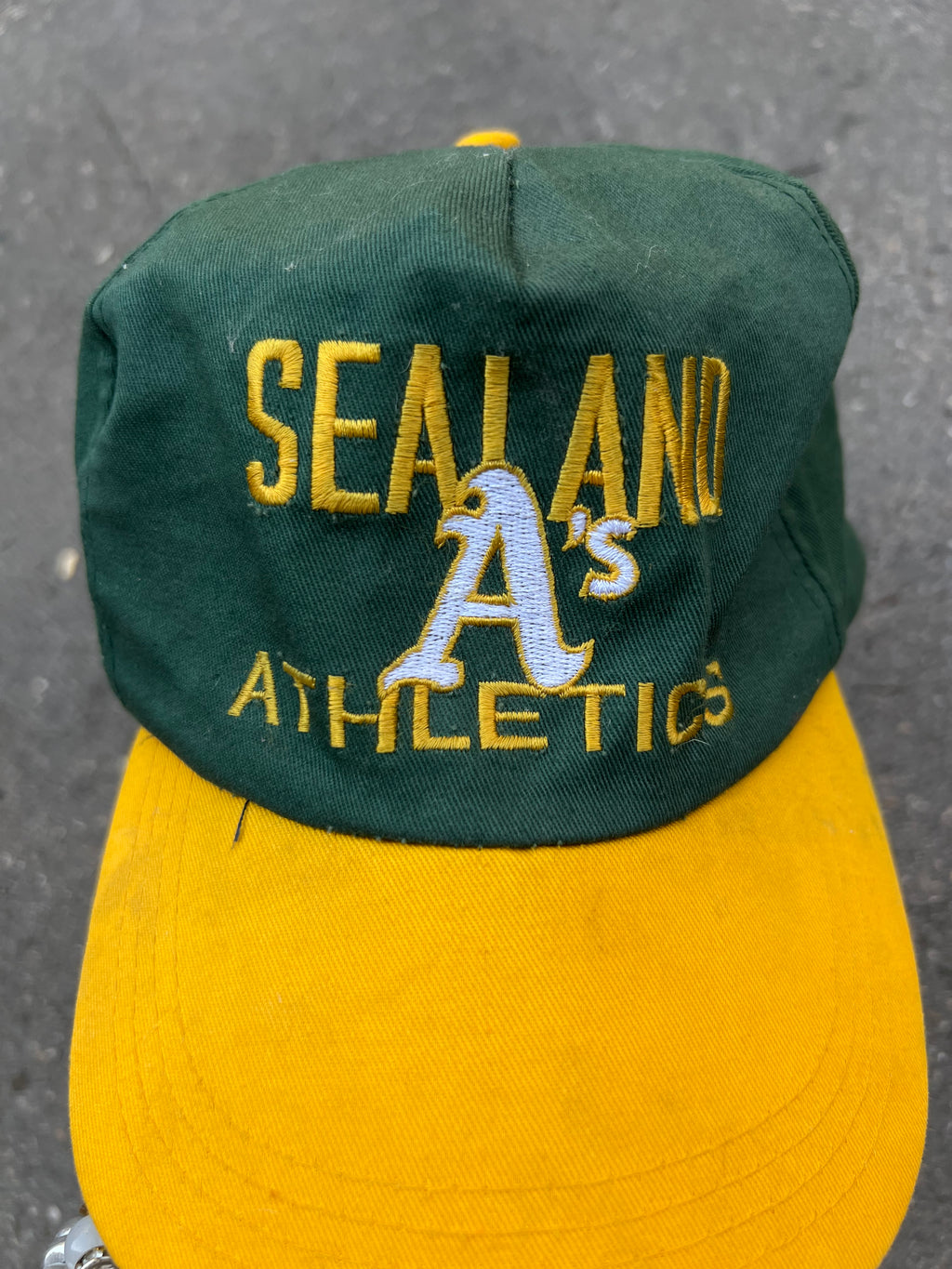 Eine grüne Cap mit gelben Sealand Schriftzug und gelben Schirm