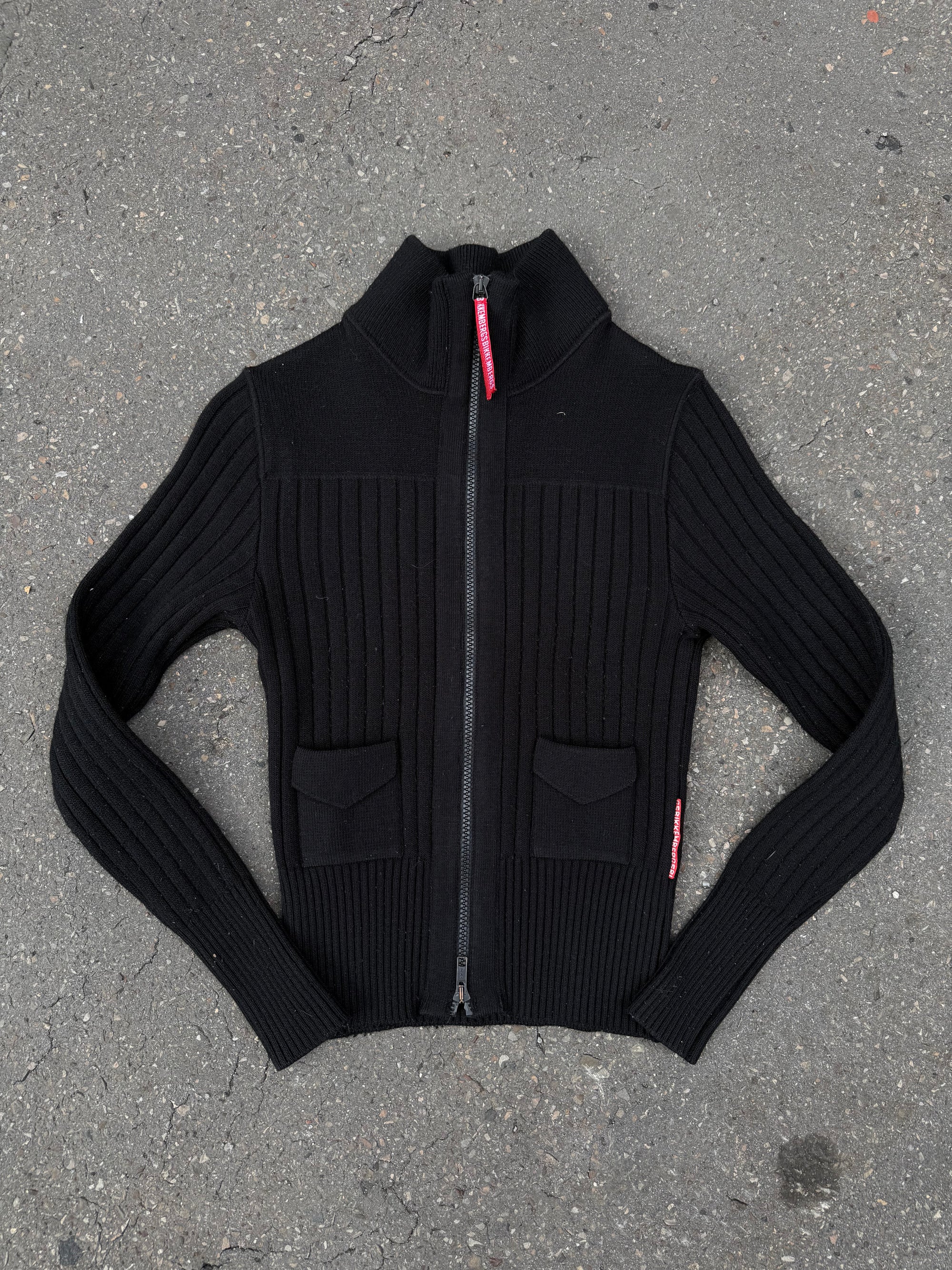 Ein schwarzer Strick Zipper von Dirk Bikkembergs mit roter Schlaufe am Reißverschluss in XS