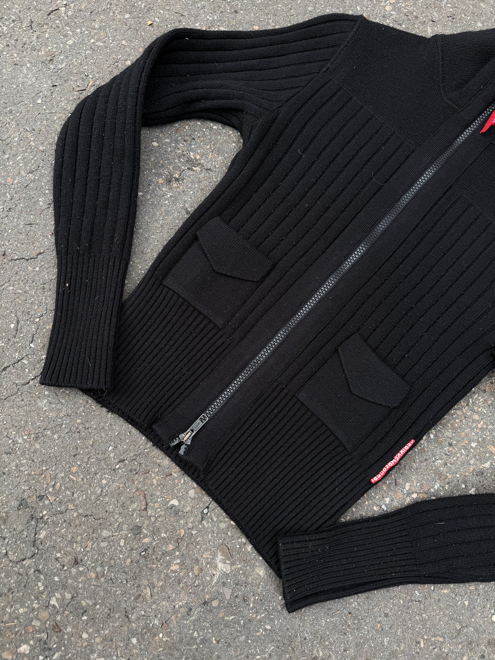 Ein schwarzer Strick Zipper von Dirk Bikkembergs mit roter Schlaufe am Reißverschluss in XS