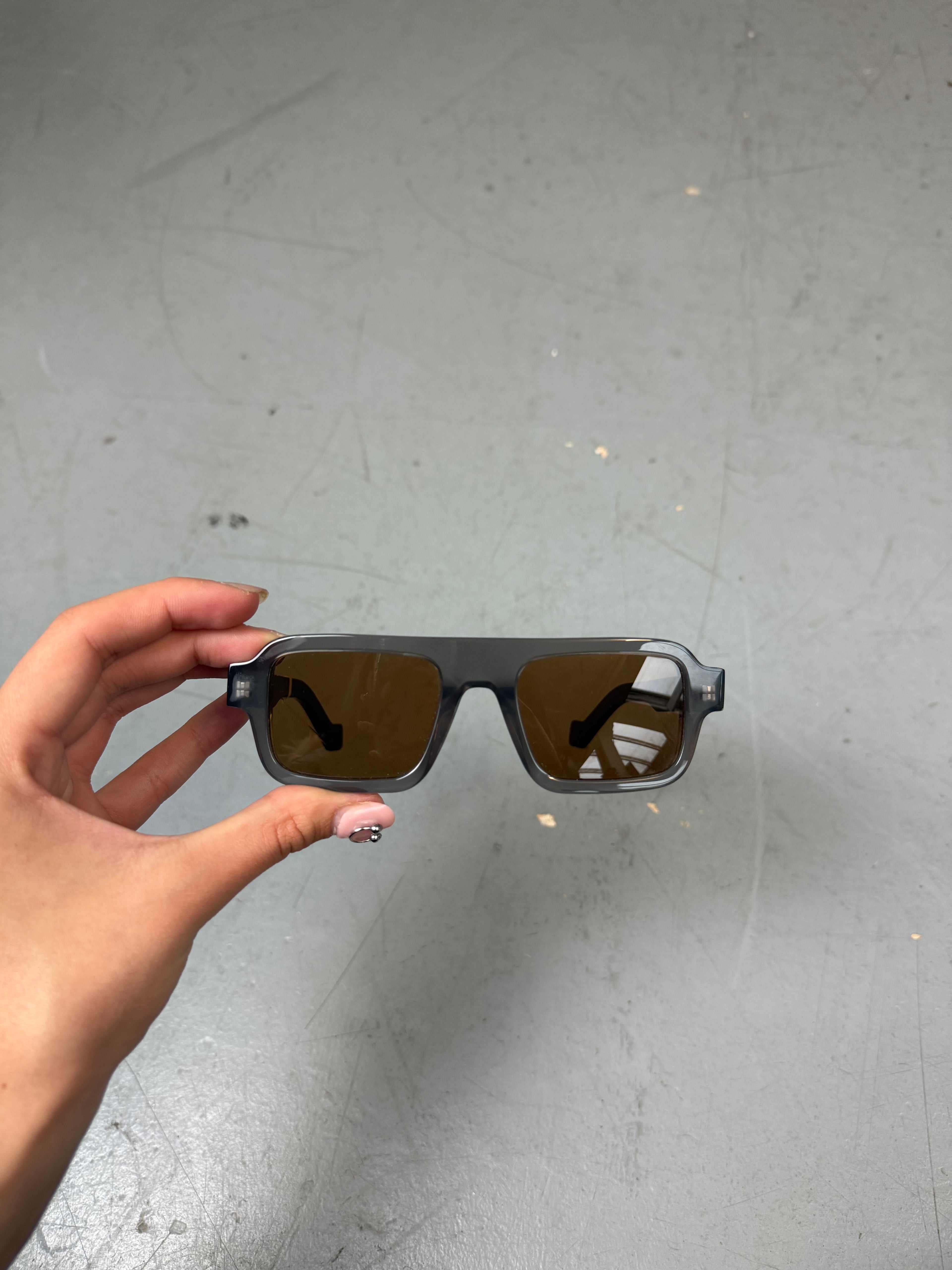 Eine rechteckige Sonnenbrille mit orangen Gläsern und grauem Gestell von Loewe 