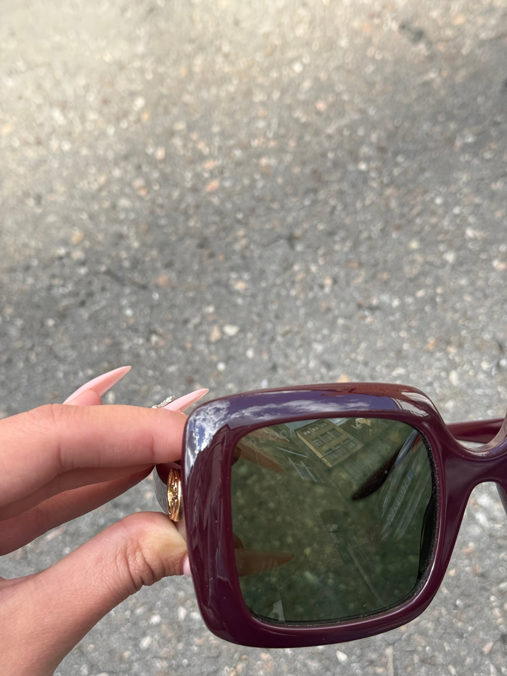 Eine burgunderrote Sonnenbrille von Gucci mit dem Logo in Gold an der Seite und großen quadratischen Gläsern