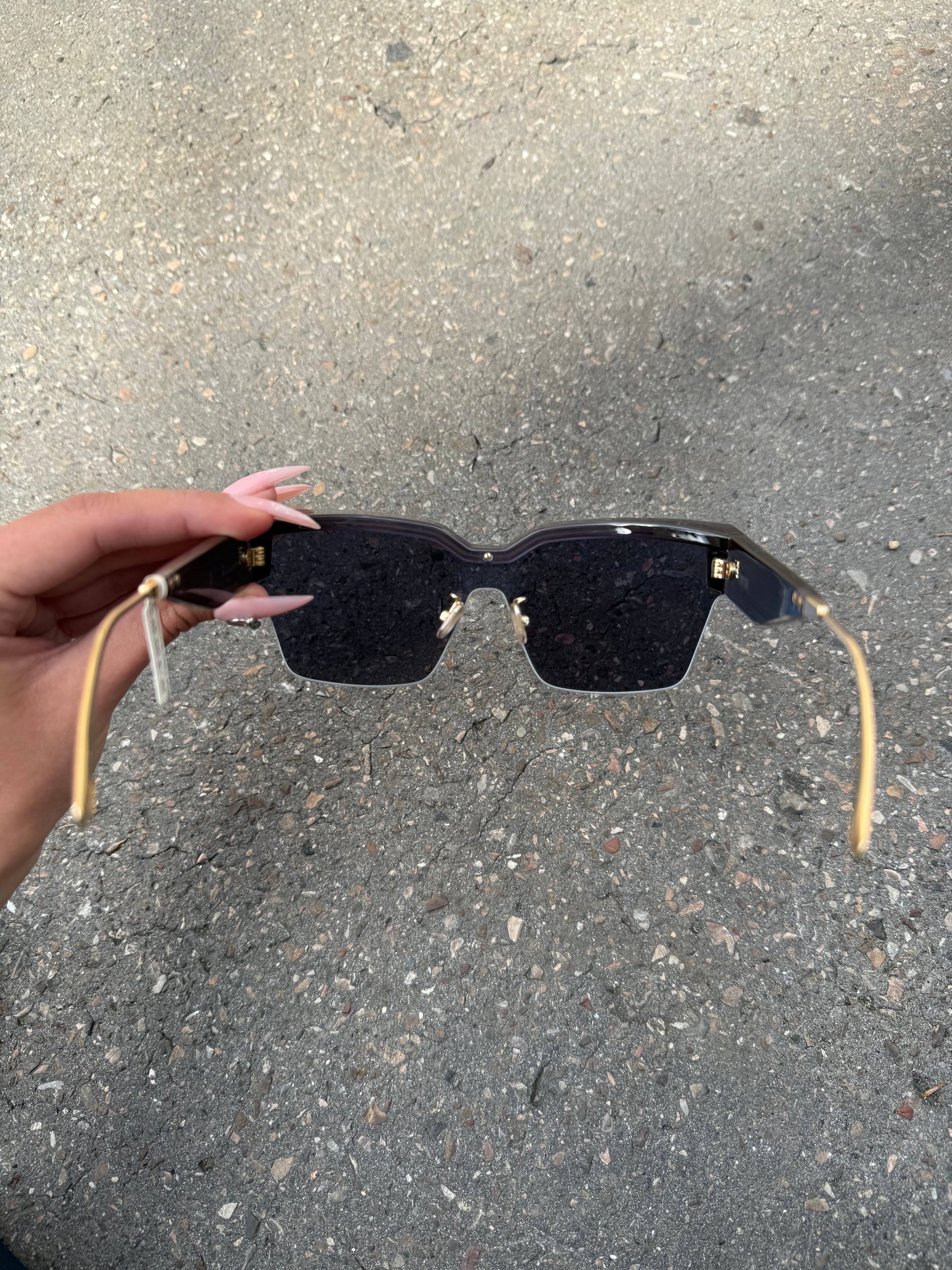 Eine schwarze Sonnenbrille von Dior mit dem Monogram auf den Gläsern und dem Markennamen auf den Bügeln