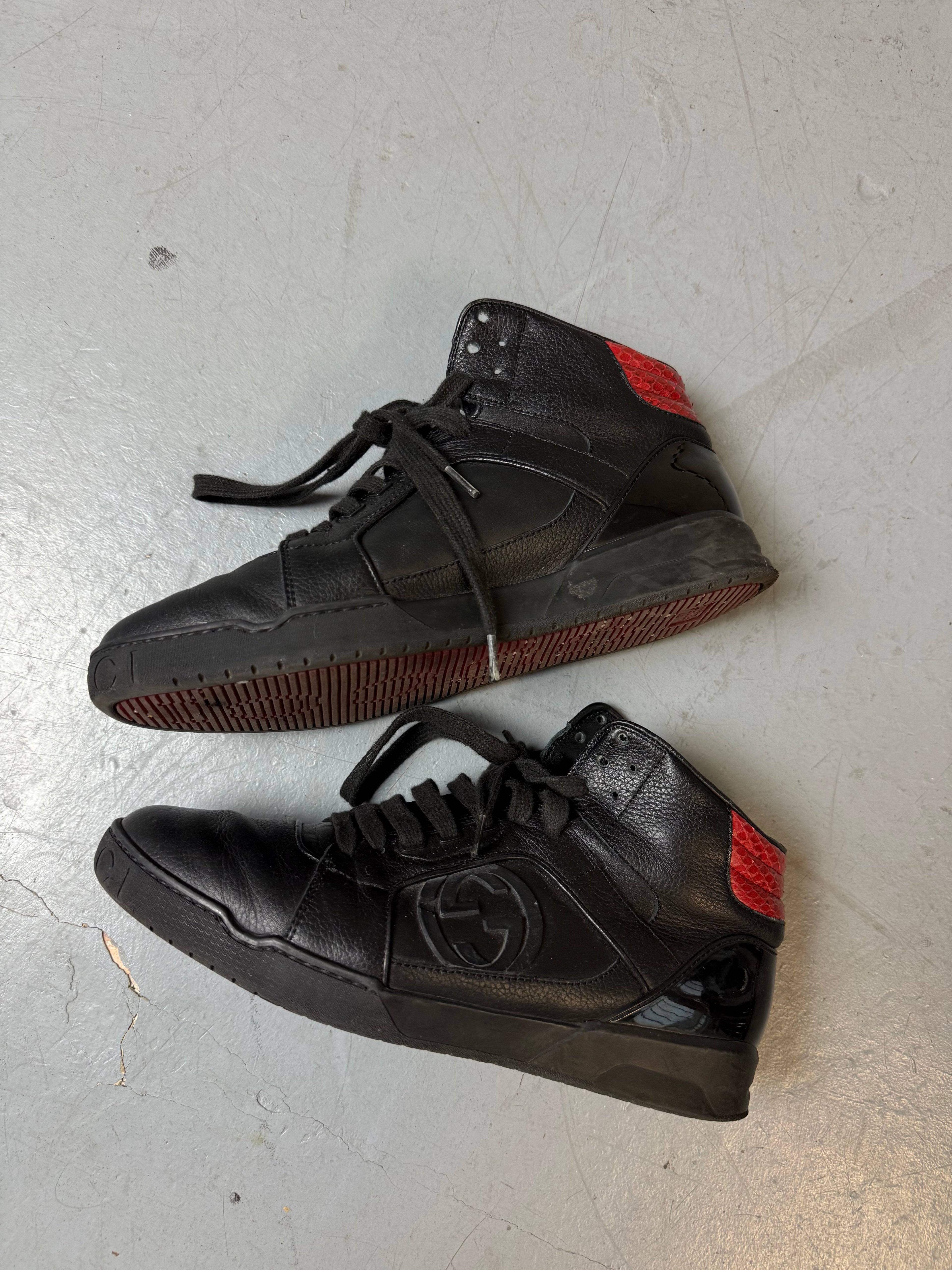 Schwarze gucci sneaker mit roten details hinten und roter sohle 