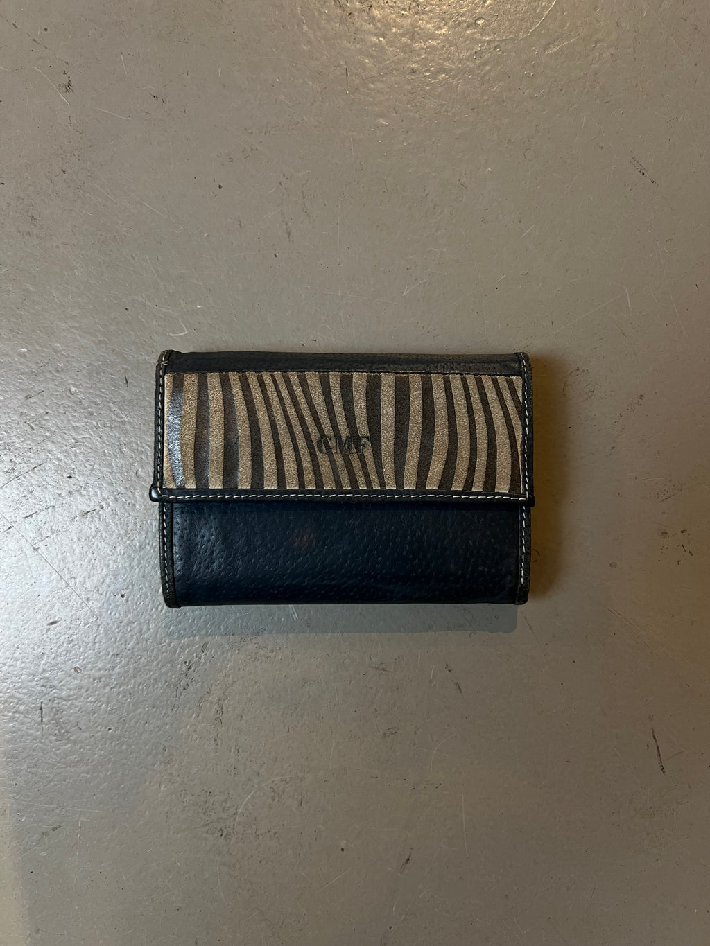 Produktbild von Grau blauem Geldbeutel mit Zebra Muster auf grauem Boden 