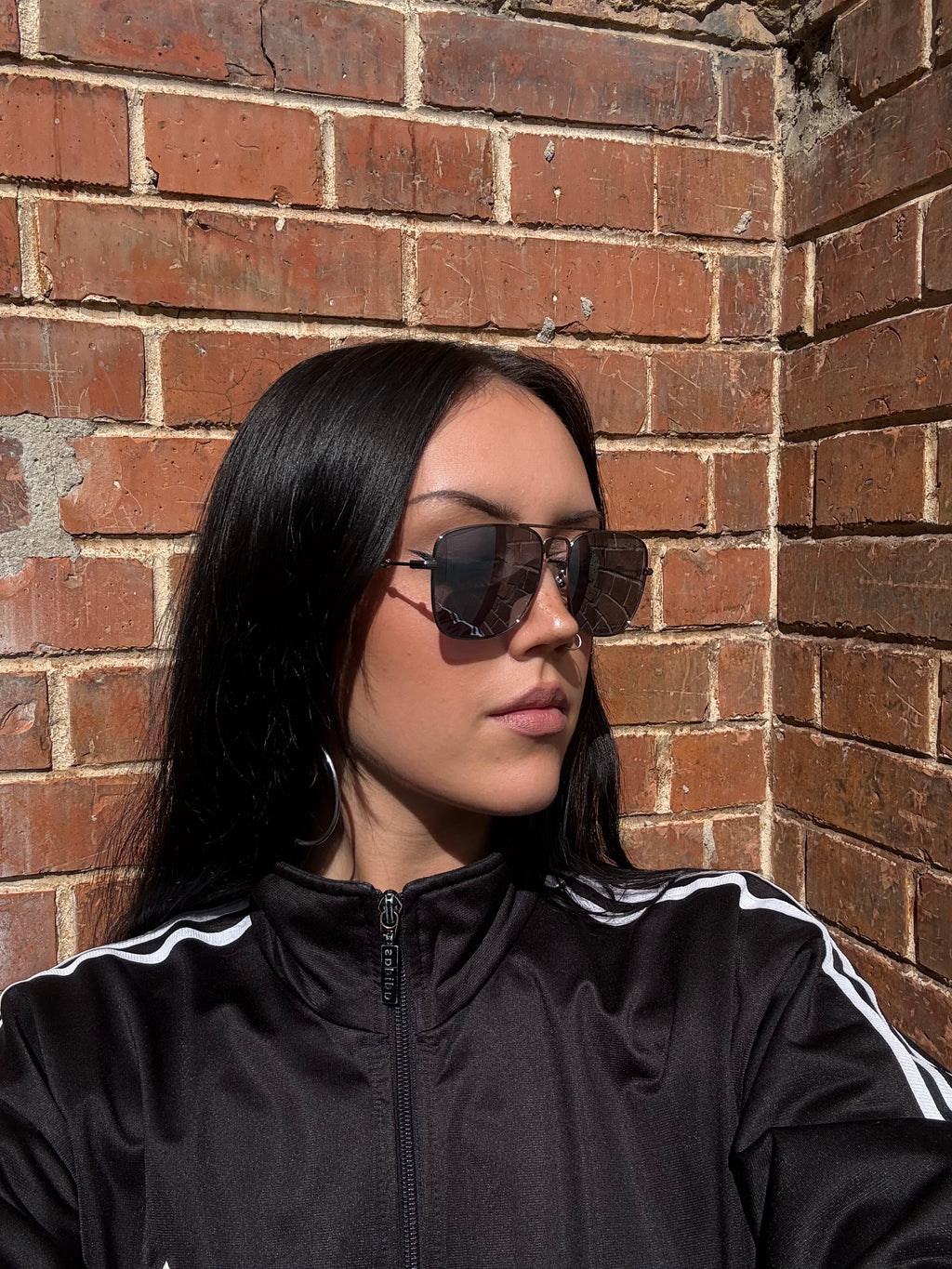 Eine eckige Sonnenbrille von gucci mit dunklen Gläsern und roten und grünen Elementen an den Bügeln 