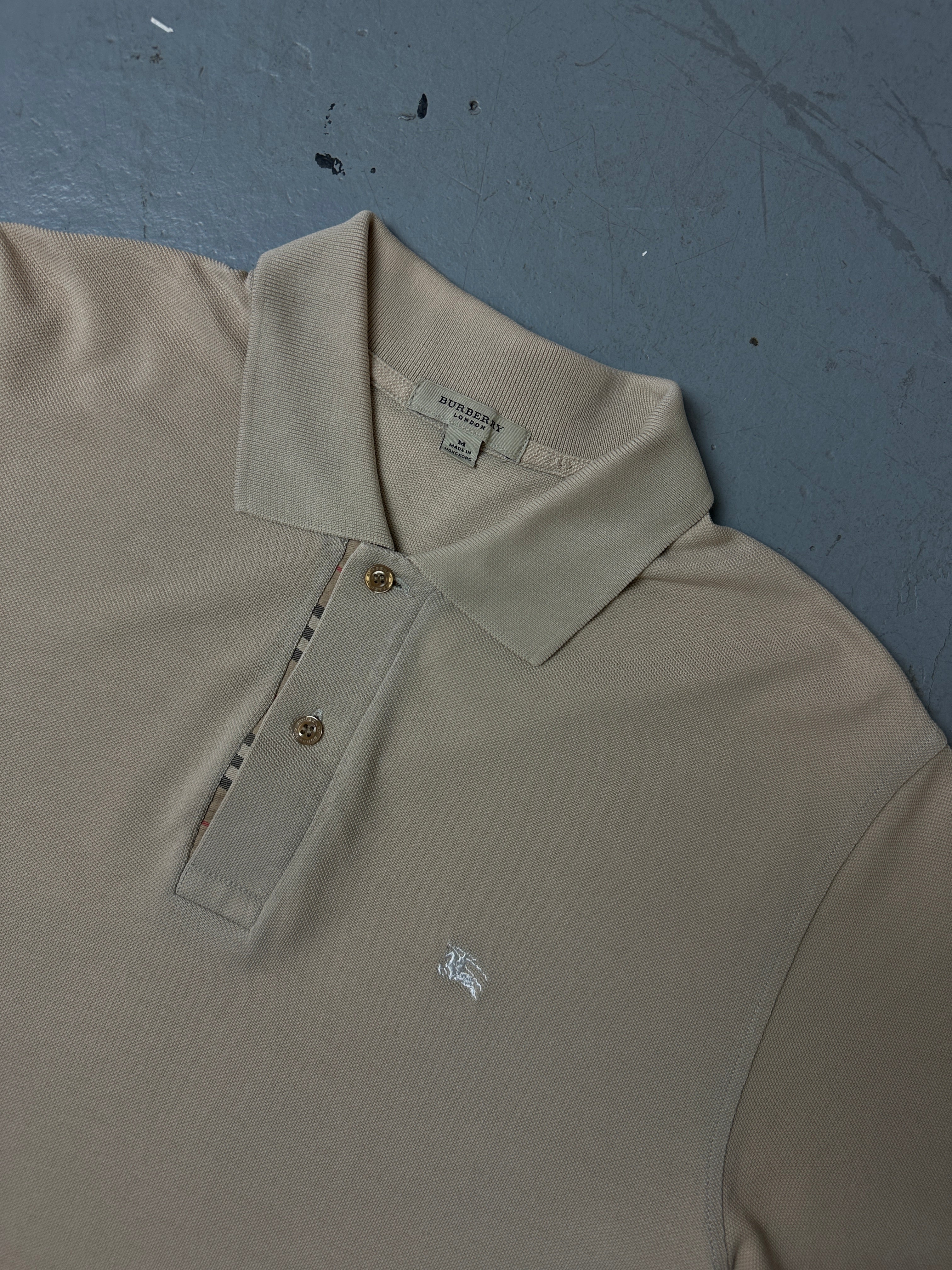 Detailliertes Produktbild von beigenen Burberry Polo auf grauem Boden 