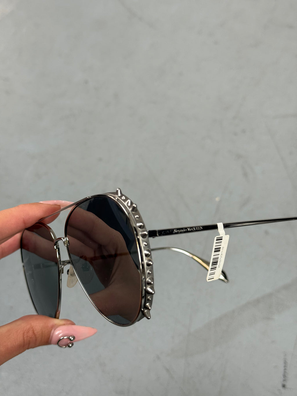 Eine Sonnenbrille von Alexander McQueen mit silbernen Nieten um die großen Gläser und dünnem Gestell 