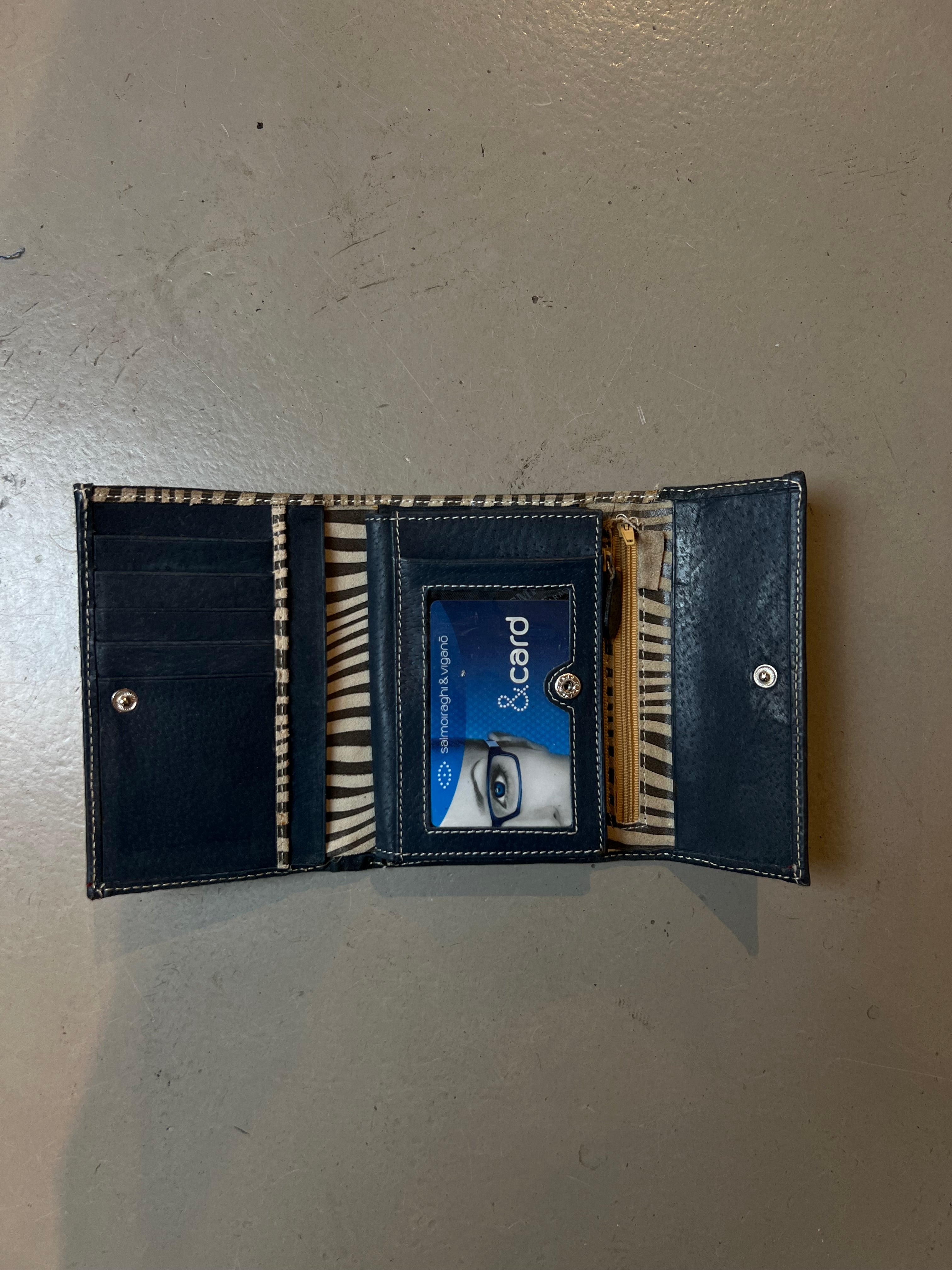 Produktbild von offenem Geldbeutel mit Zebra Muster auf grauem Boden 