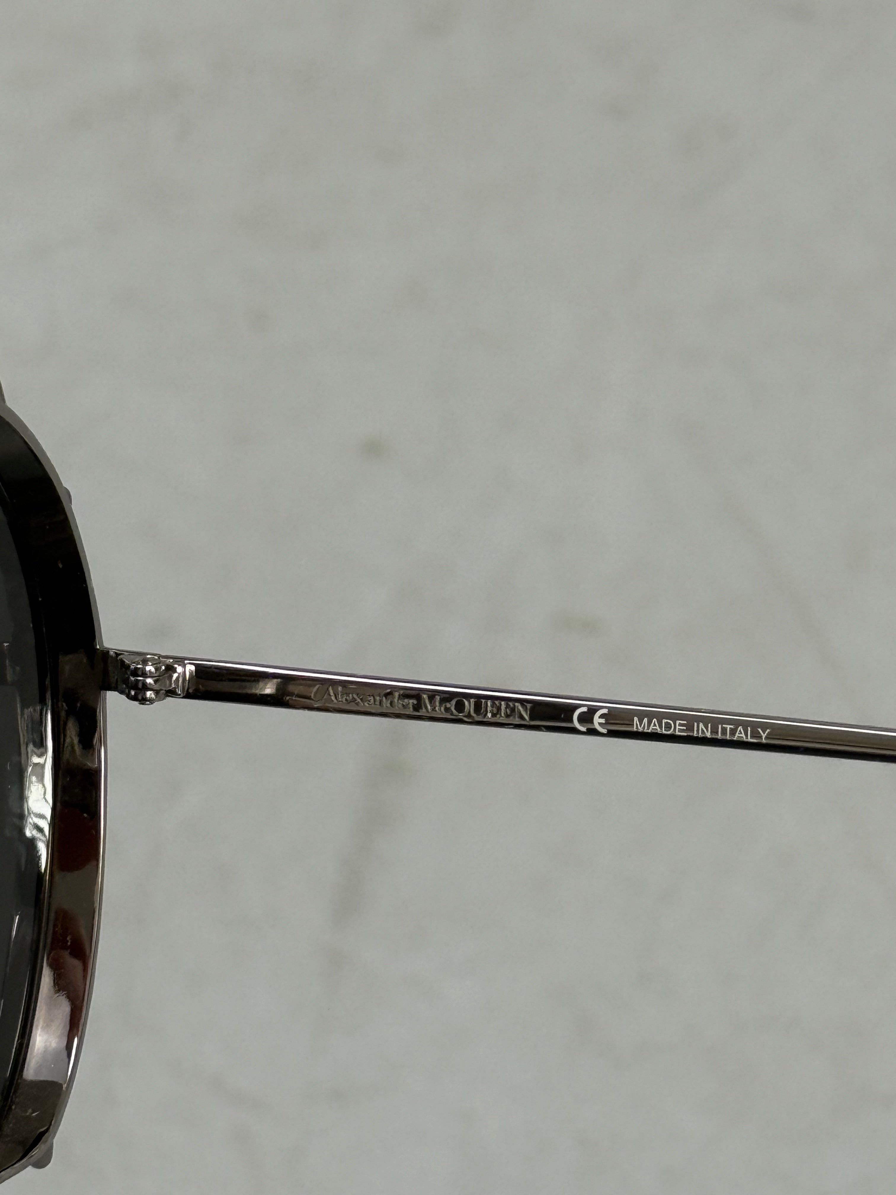 Eine Sonnenbrille von Alexander McQueen mit silbernen Nieten um die großen Gläser und dünnem Gestell 