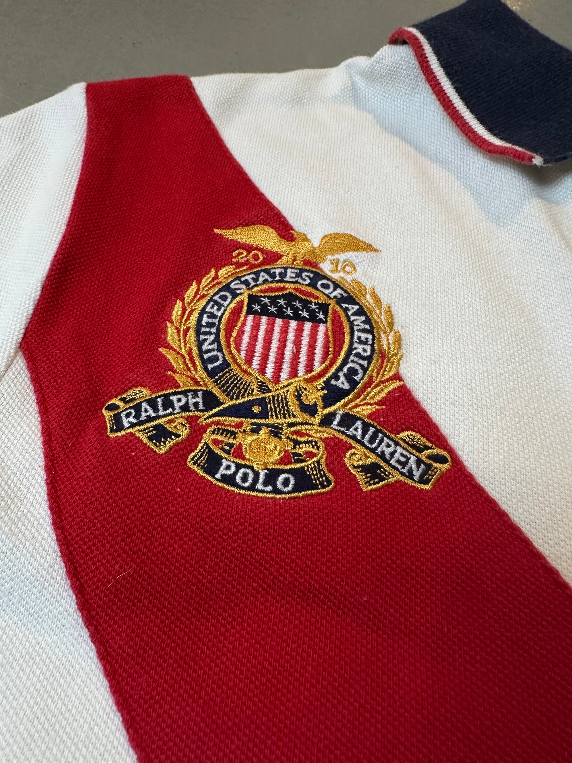 Ein weißes Ralph Lauren Polo mit großem Reiter auf der Brust und roter Strefien in M