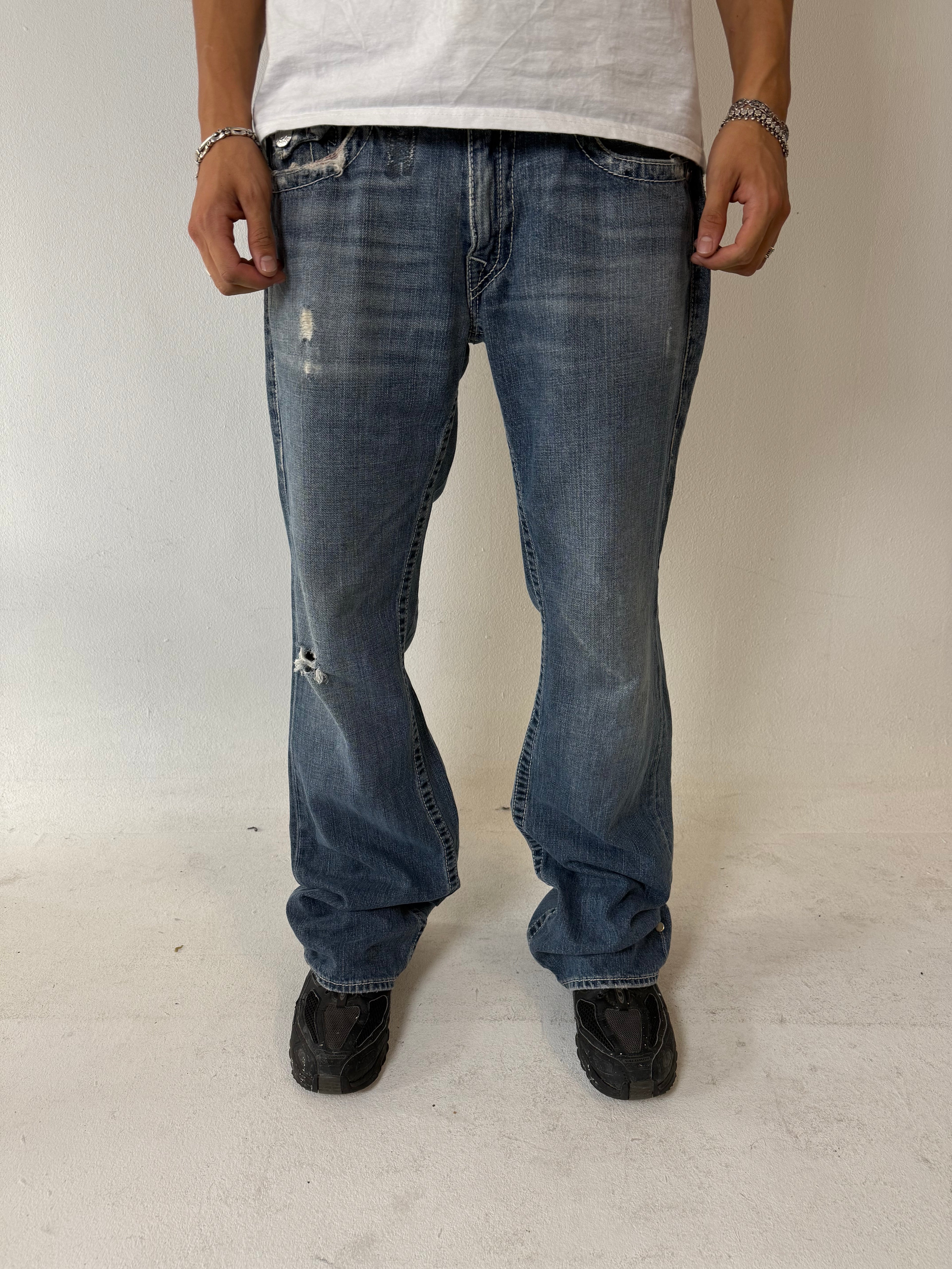 Eine blau-graue baggy True Religion Jeans mit weißen Hufeisen Stitching
