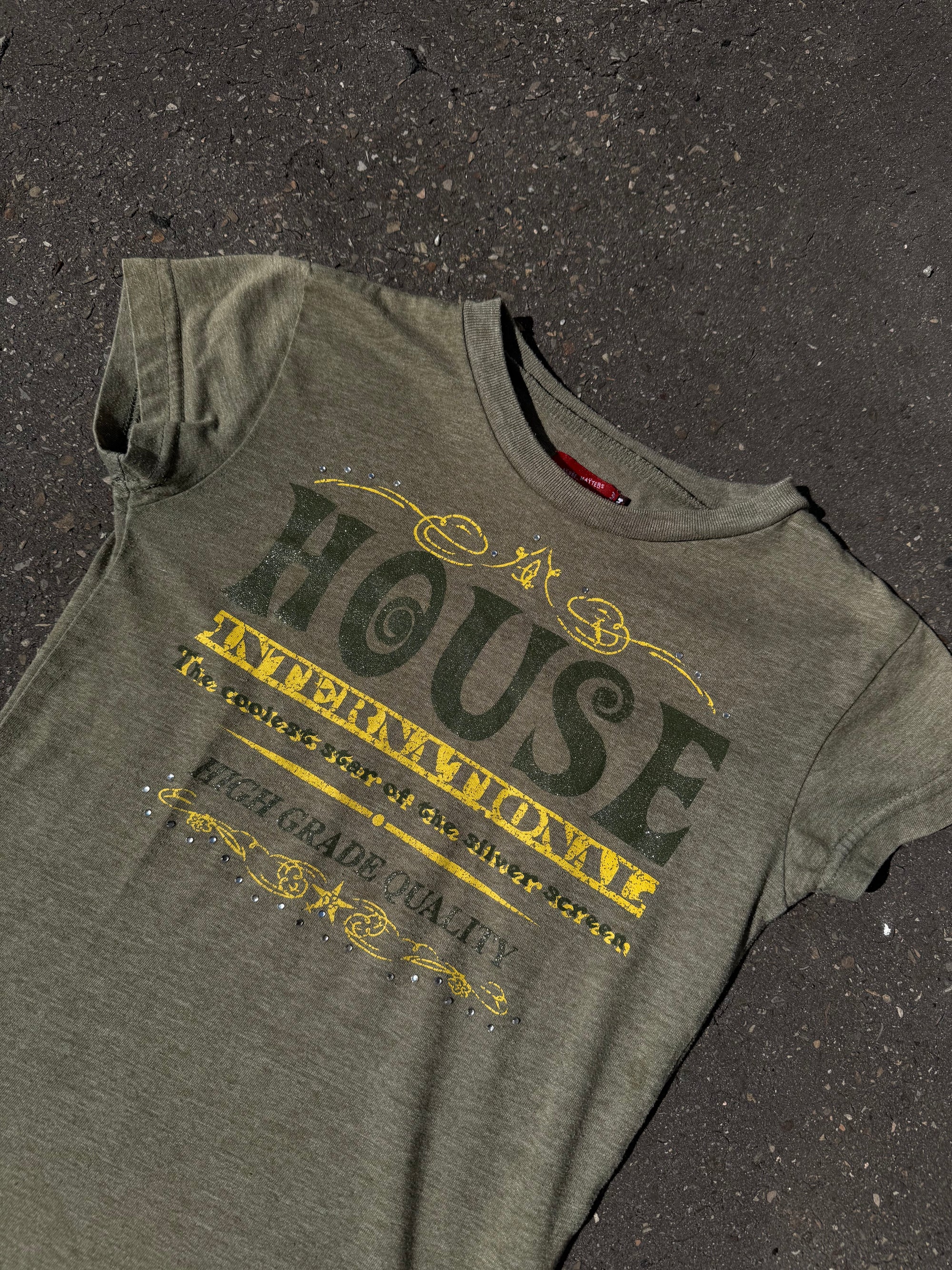 Ein Khaki Baby Tee mit dunkelgrünem und gelbem Print auf der Vorderseite 