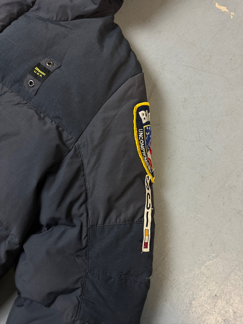 Detailliertes Produktbild von Grauer Blauer Daunen Jacke in L für grauem Boden