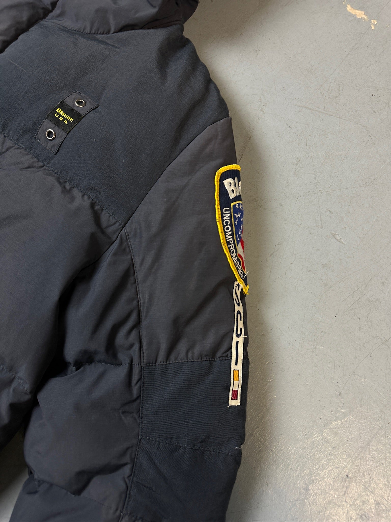 Detailliertes Produktbild von Grauer Blauer Daunen Jacke in L für grauem Boden