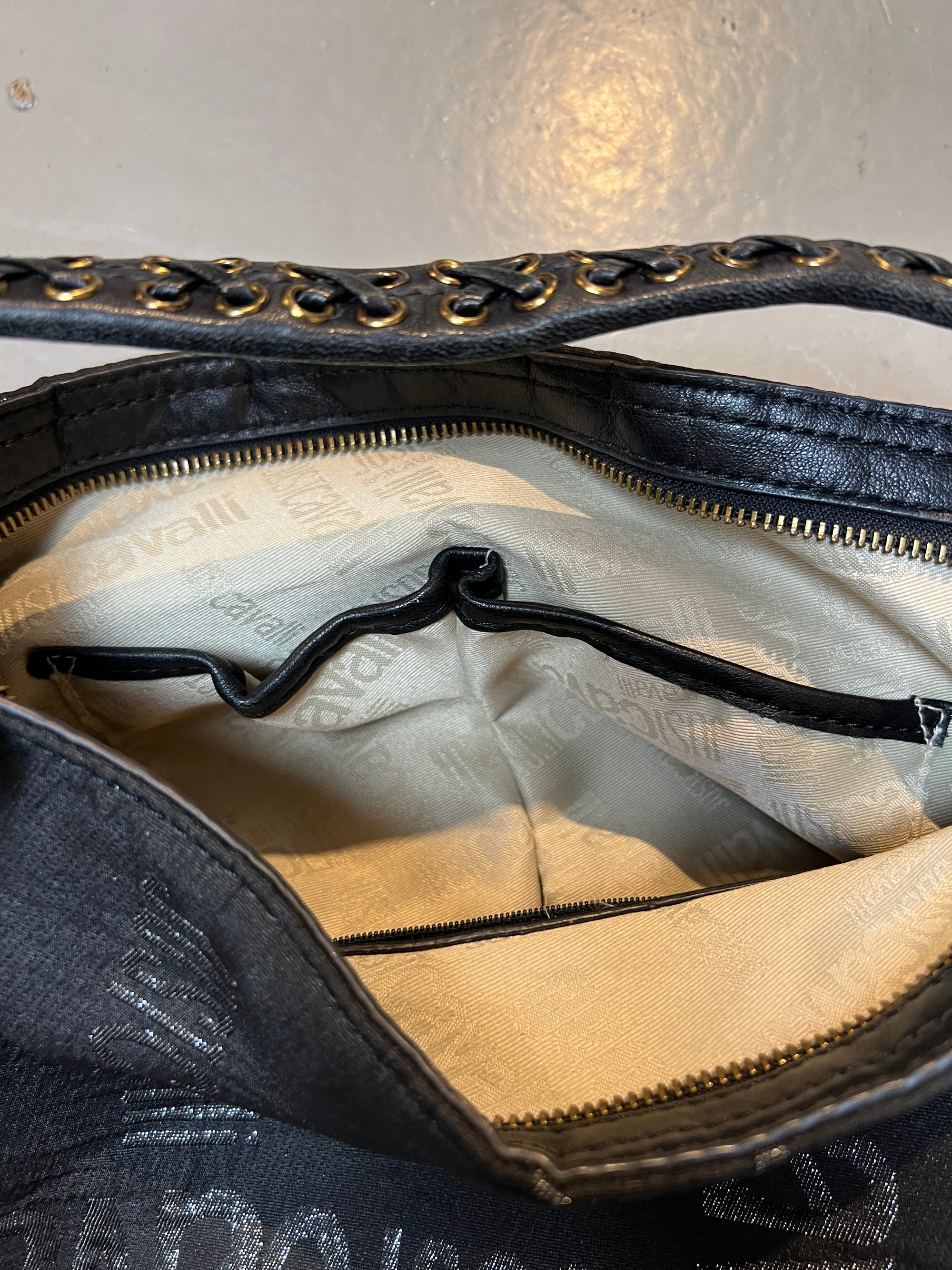 Schwarze schultertasche von just cavalli. Goldene Hardware, Monogramm Muster. Produktbild vor grauem Hintergrund. Innenansicht des Futters. 