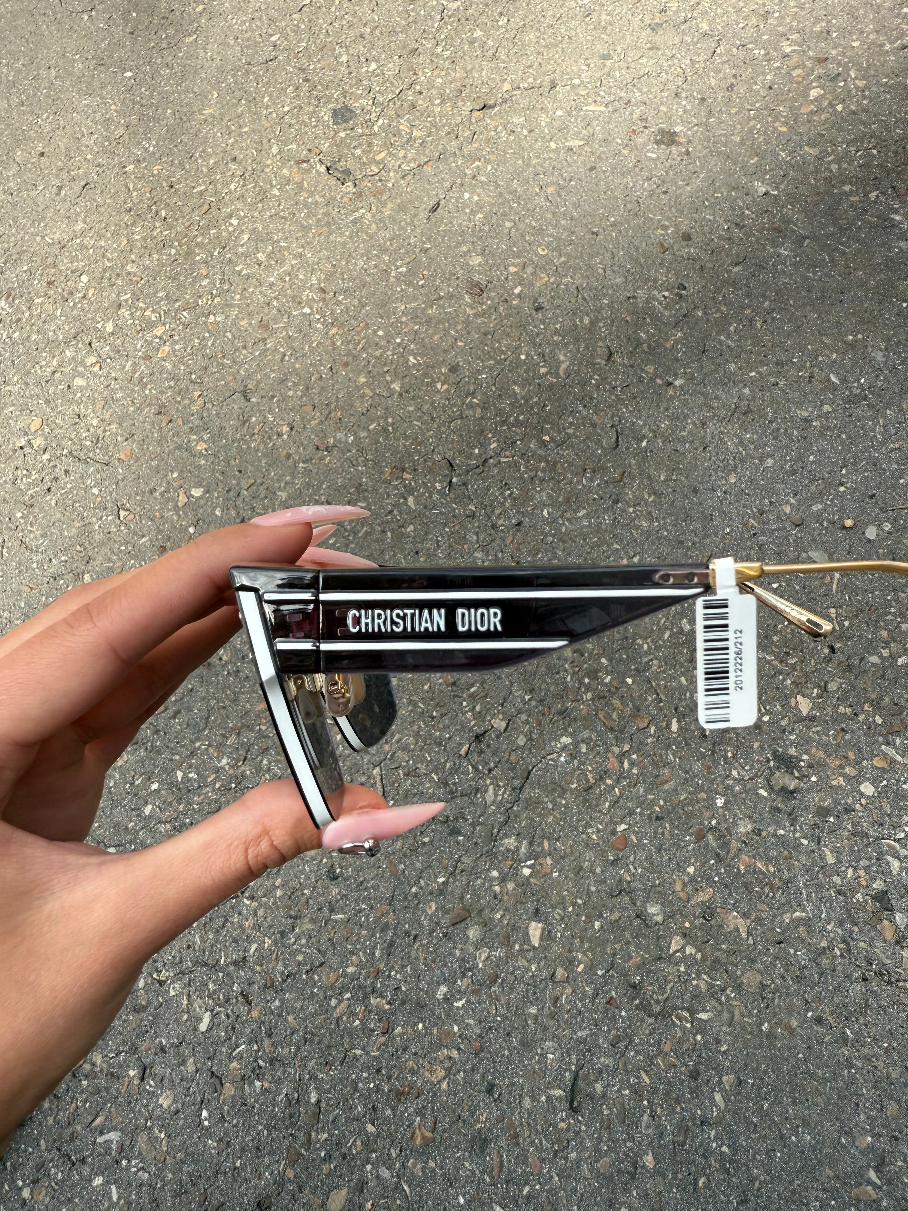 Eine schwarze Sonnenbrille von Dior mit dem Monogram auf den Gläsern und dem Markennamen auf den Bügeln