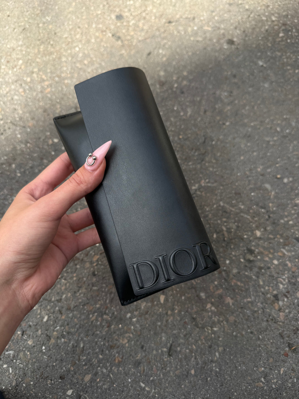 Eine schwarze Sonnenbrille von Dior mit dem Monogram auf den Gläsern und dem Markennamen auf den Bügeln