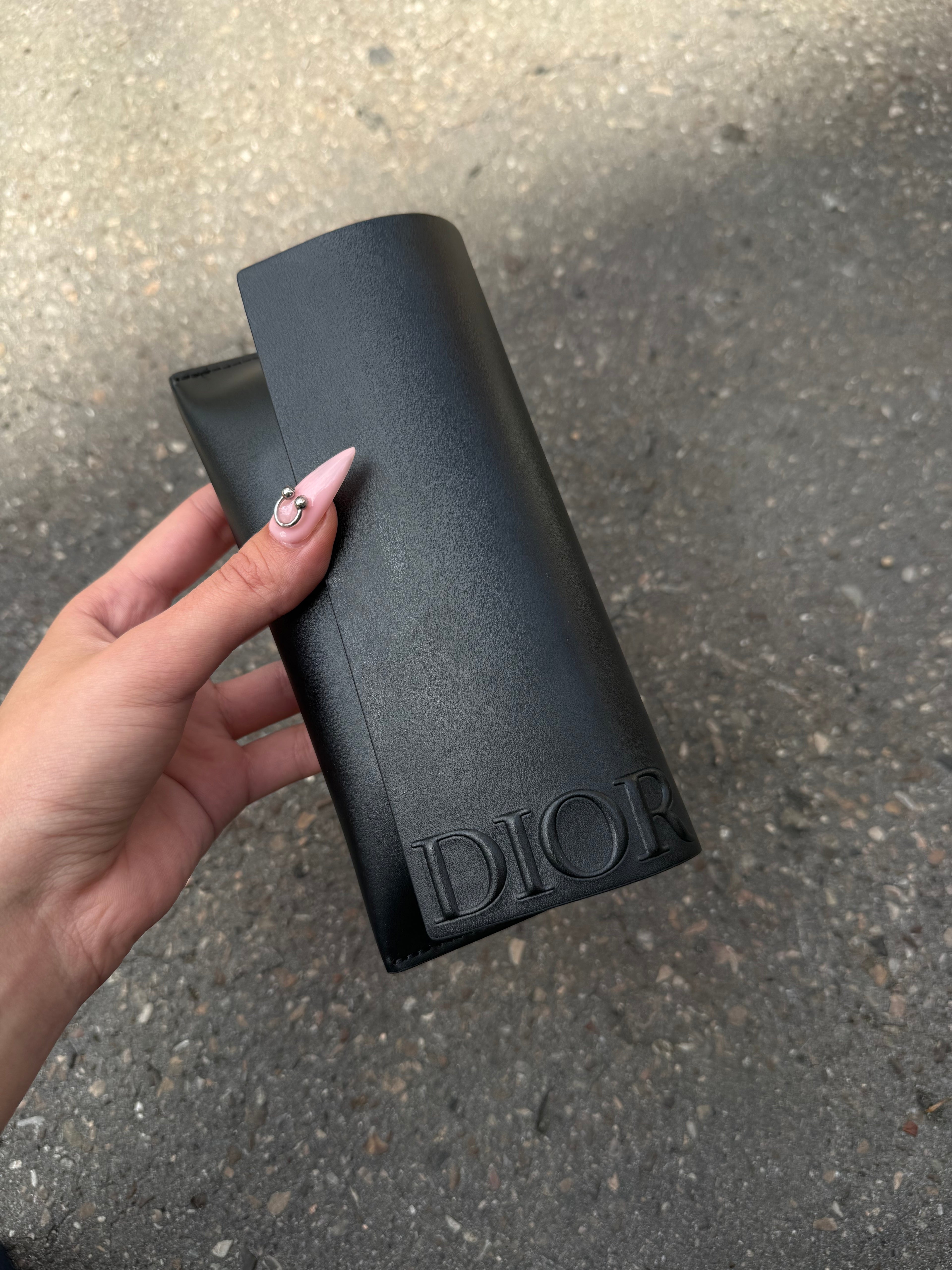 Eine schwarze Sonnenbrille von Dior mit dem Monogram auf den Gläsern und dem Markennamen auf den Bügeln