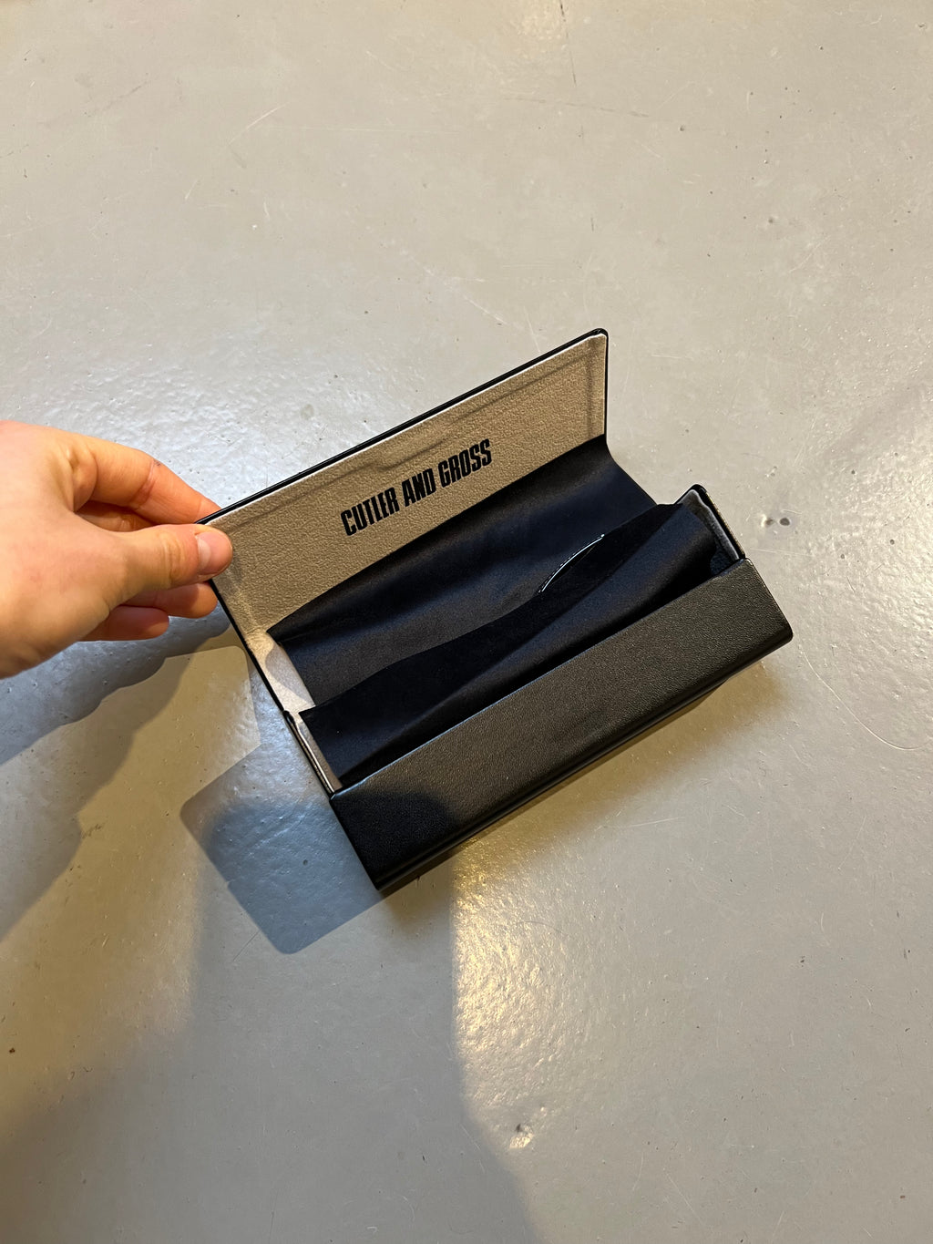 Produktbild der Cutler and Gross Sunglasses Black Glitter von oben mit Case vor grauem Hintergrund.