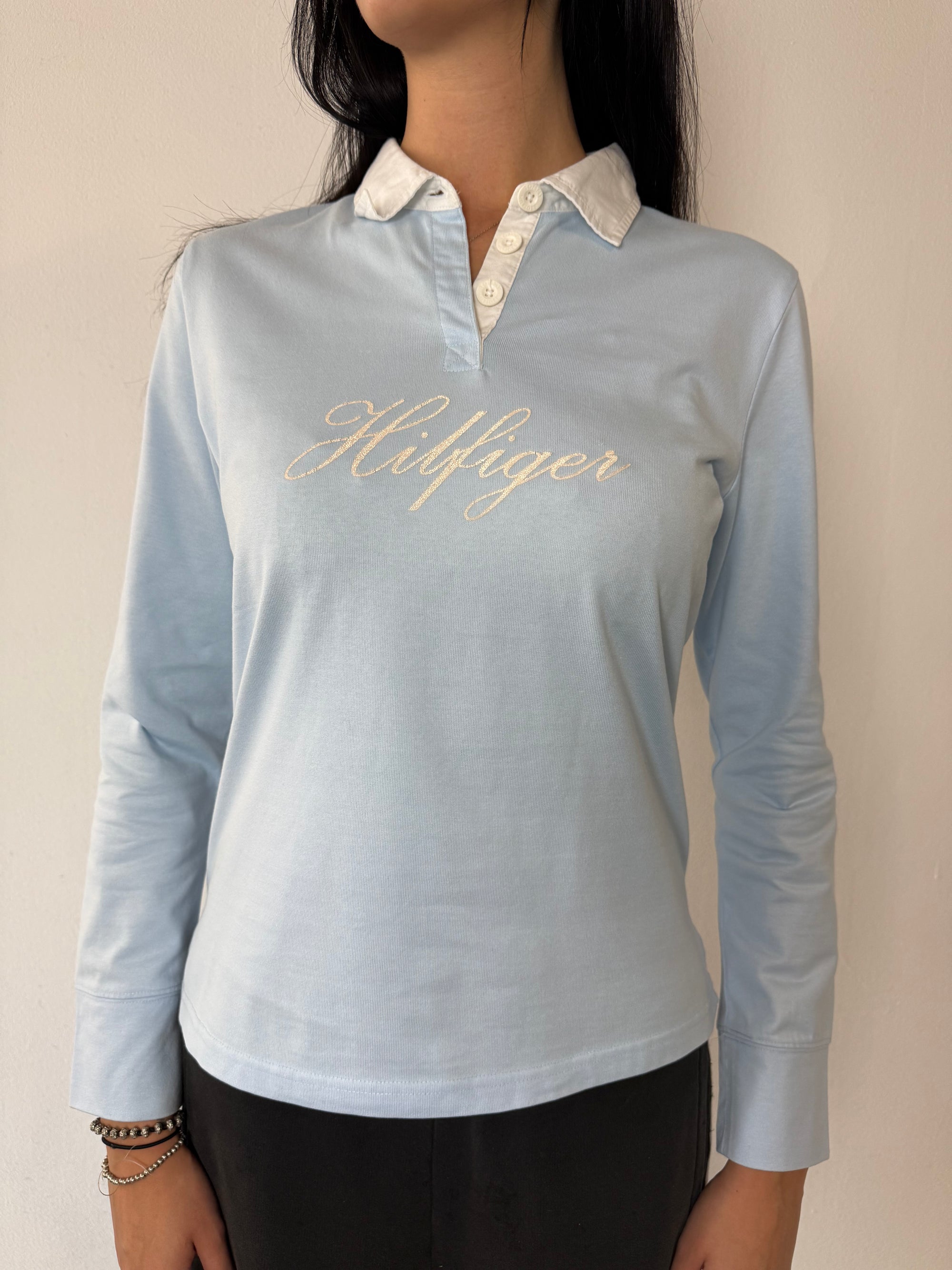 Ein babyblaues langärmliges Polo mit weißem Kragen und Hilfiger in Silber auf der Brust geschrieben