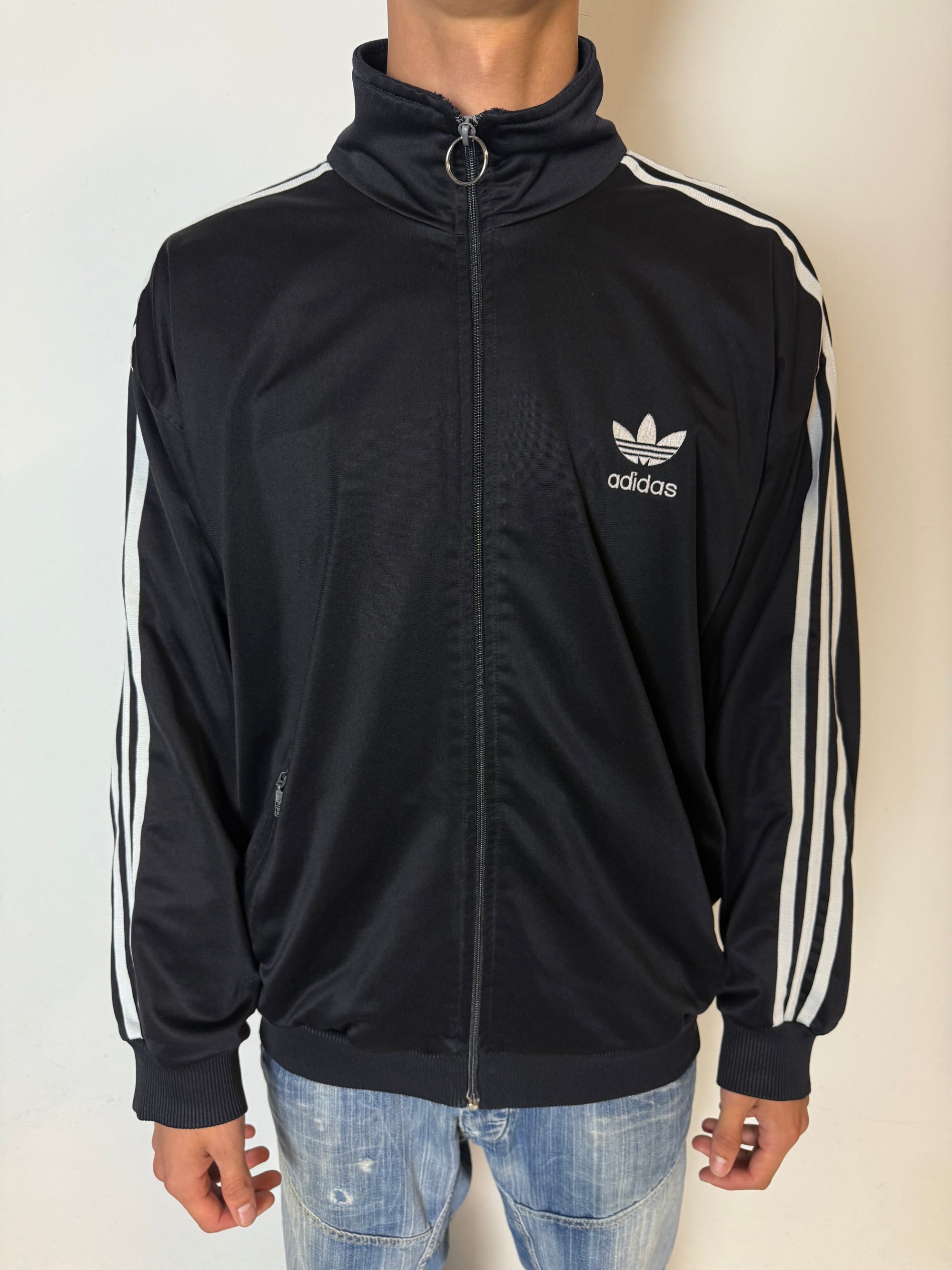 Eine schwarze vintage Adidas Track Jacke mit weißen Streifen und Firebird Logo 