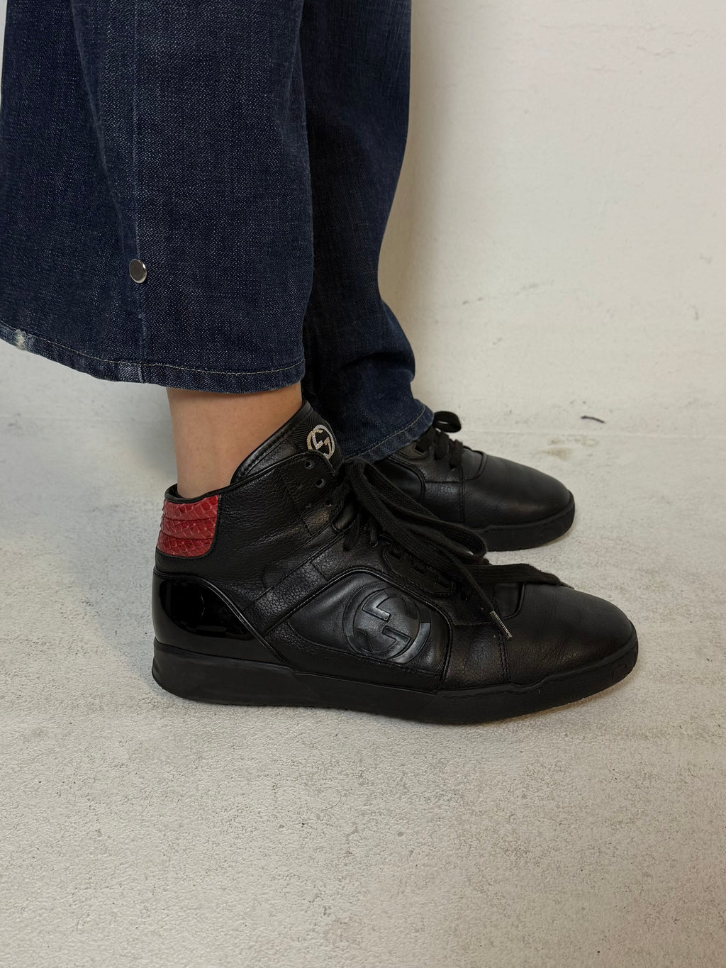 Schwarze gucci sneaker mit roten details hinten und roter sohle 