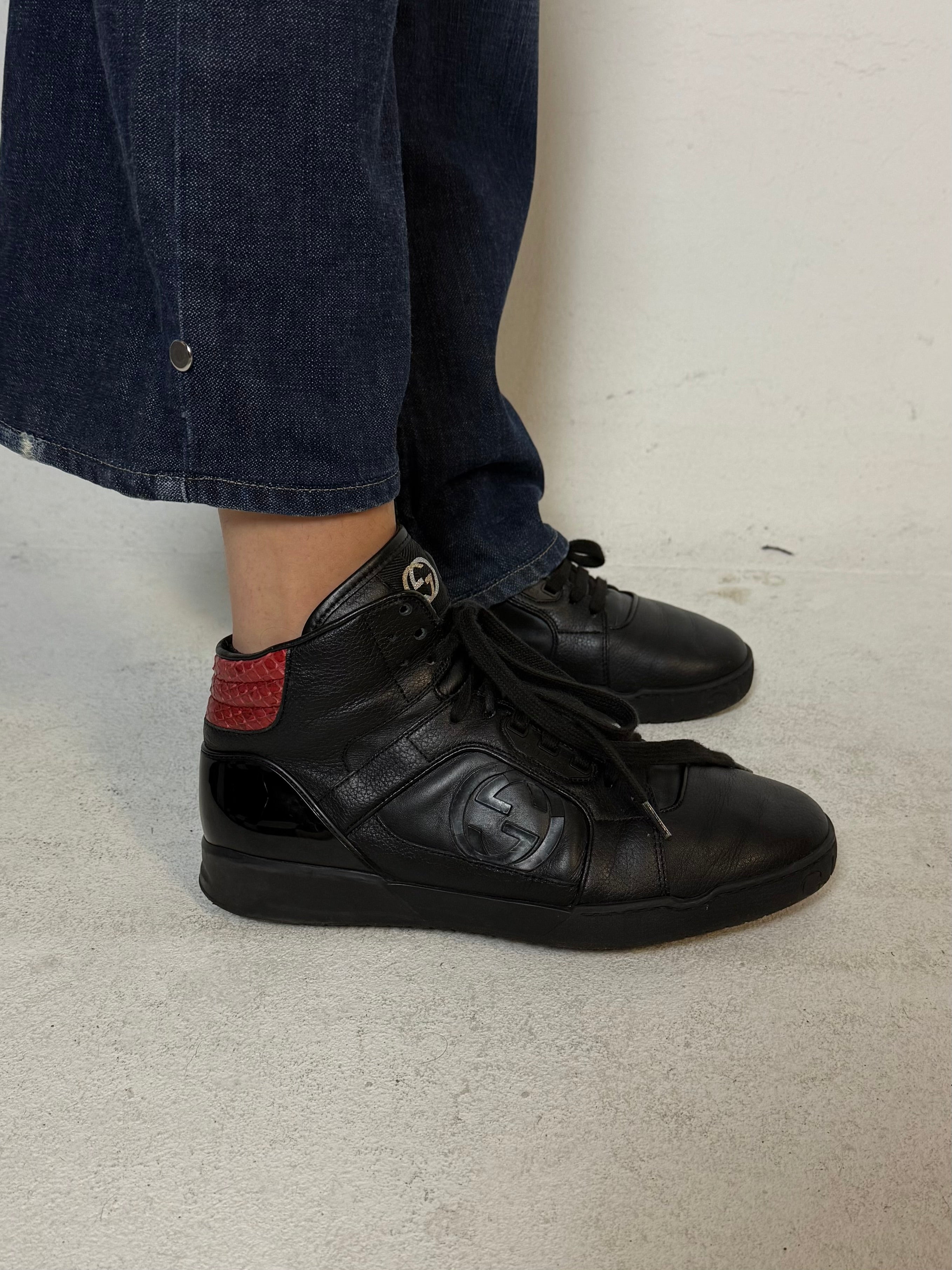 Schwarze gucci sneaker mit roten details hinten und roter sohle 