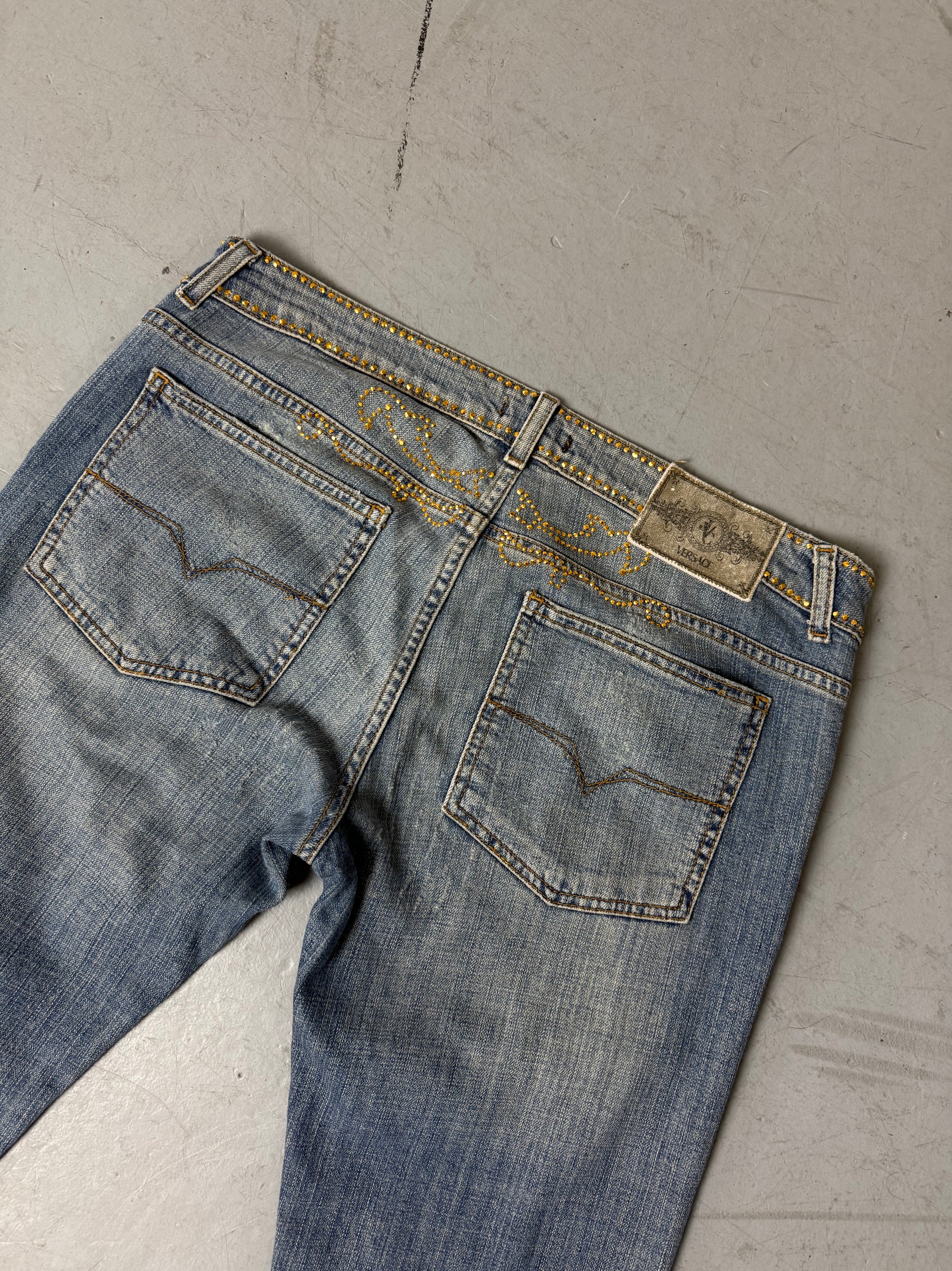 Eine low waist blue washed Versace Jeans im Bootcut Schnitt mit goldenen rhinestones um den Bund und am Bein 