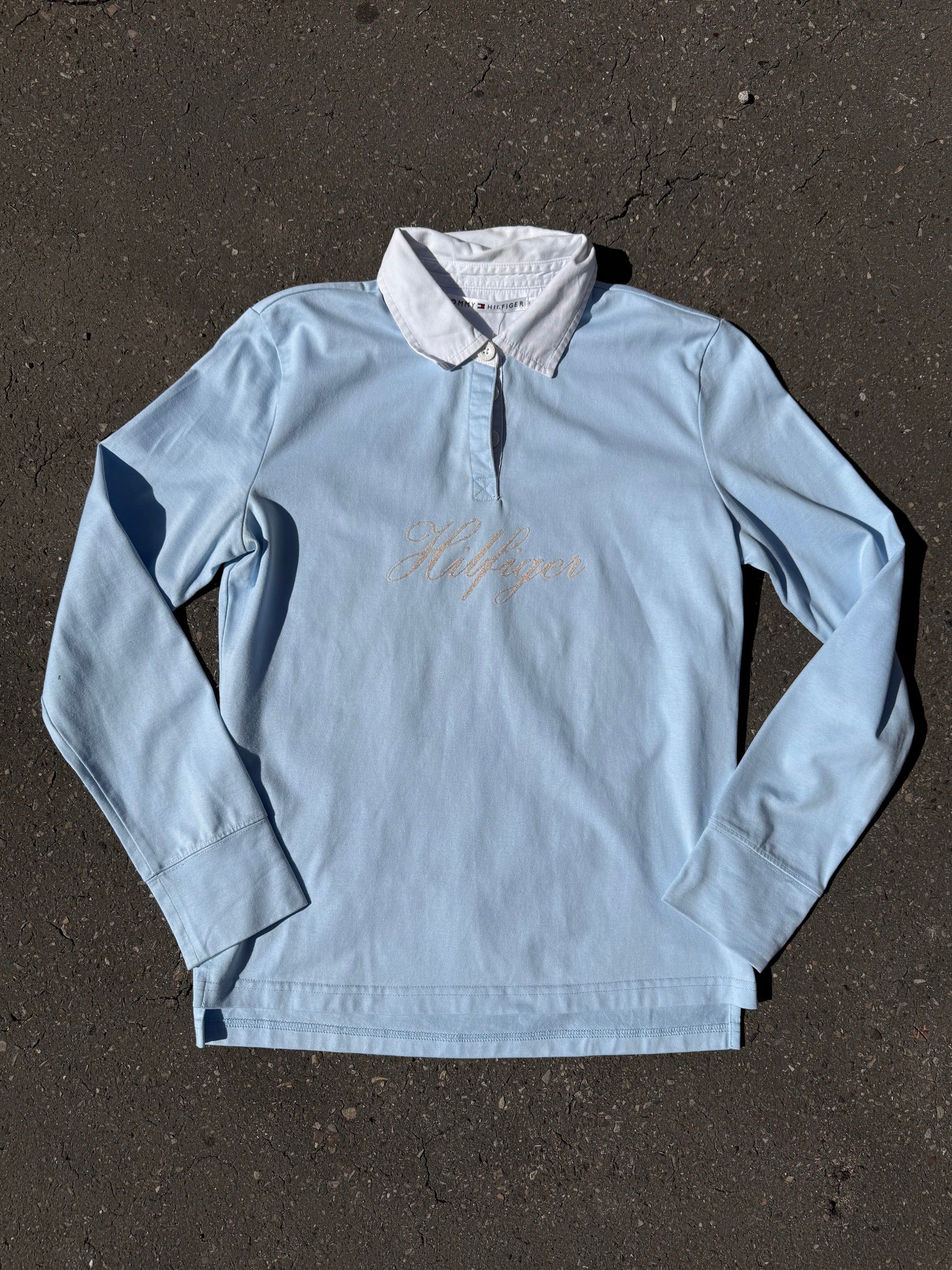 Ein babyblaues langärmliges Polo mit weißem Kragen und Hilfiger in Silber auf der Brust geschrieben 