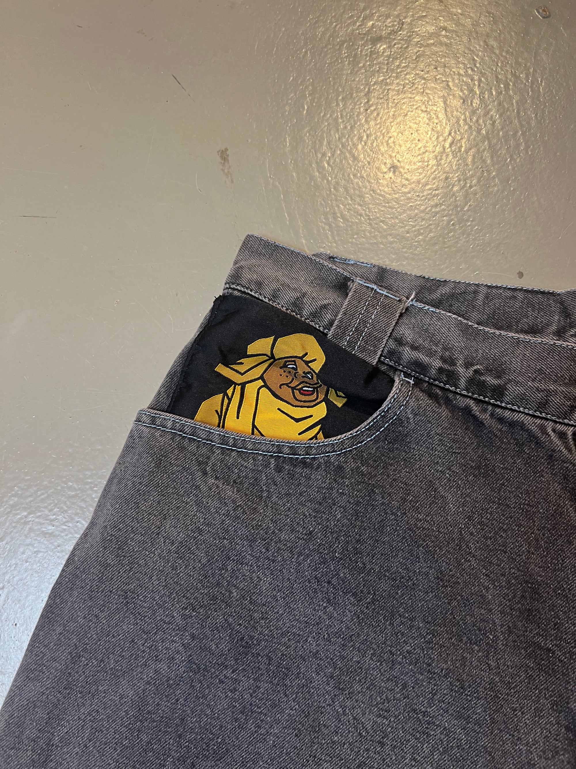 bild von der Hosentasche mit Print von grauen baggy Fubu Shorts mit gelbem Backprint von vorne