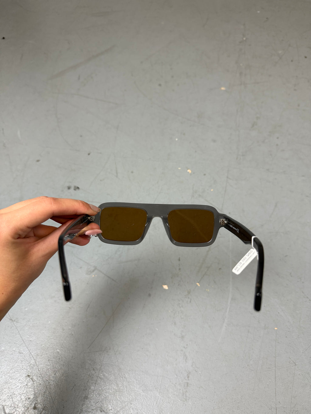 Eine rechteckige Sonnenbrille mit orangen Gläsern und grauem Gestell von Loewe 