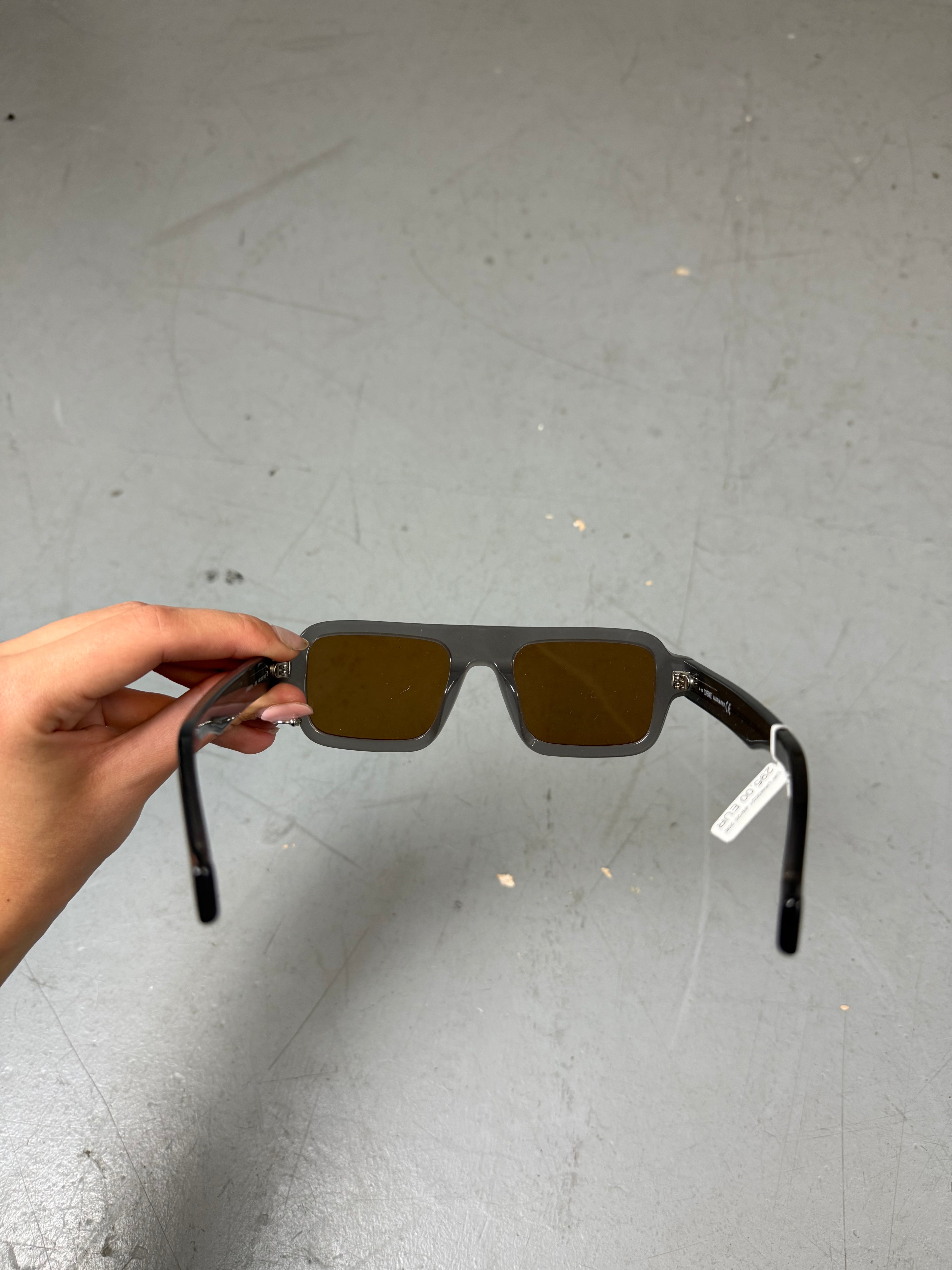 Eine rechteckige Sonnenbrille mit orangen Gläsern und grauem Gestell von Loewe 