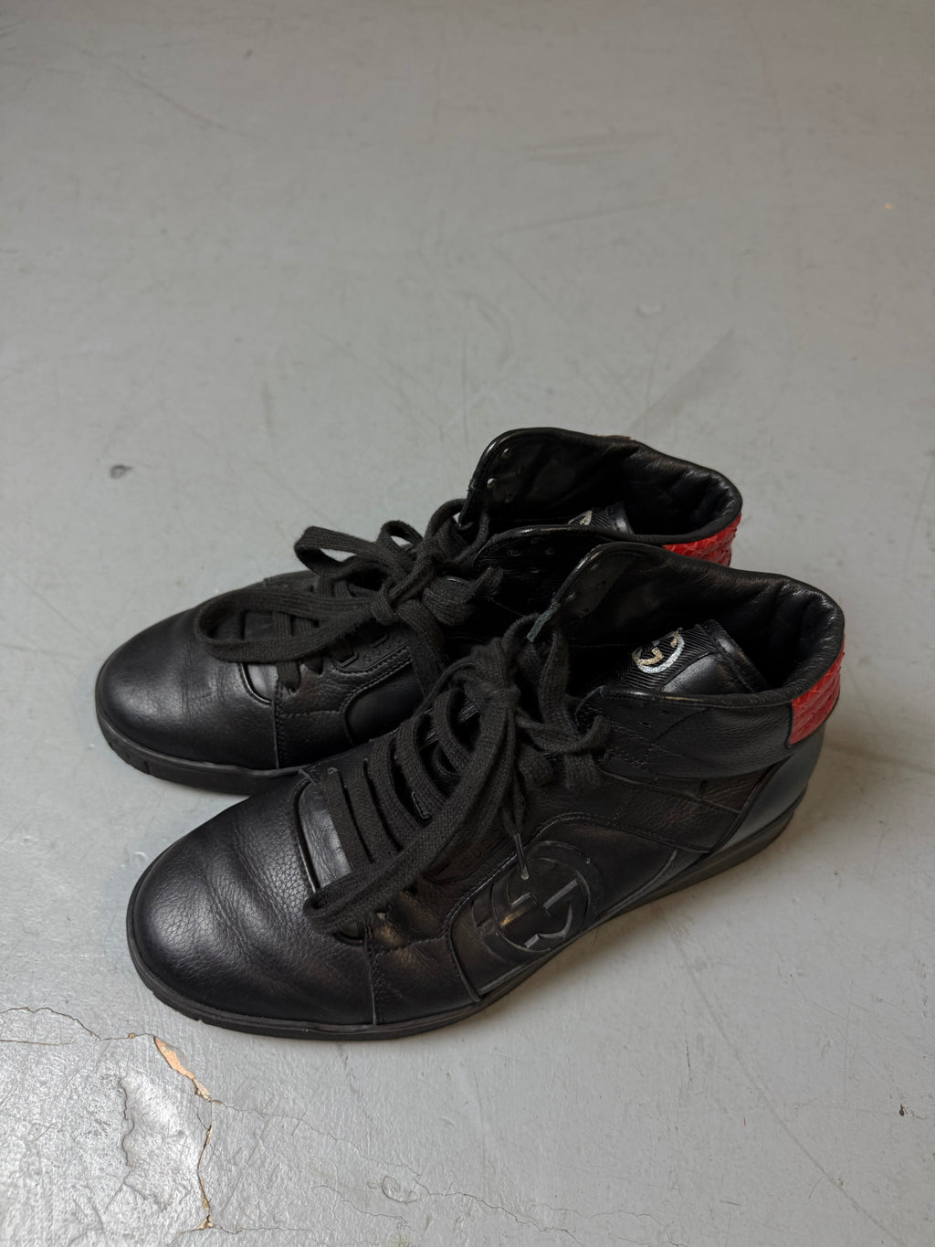 Schwarze gucci sneaker mit roten details hinten und roter sohle 