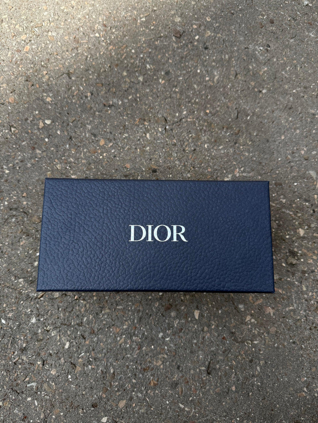 Eine schwarze Sonnenbrille von Dior mit dem Monogram auf den Gläsern und dem Markennamen auf den Bügeln