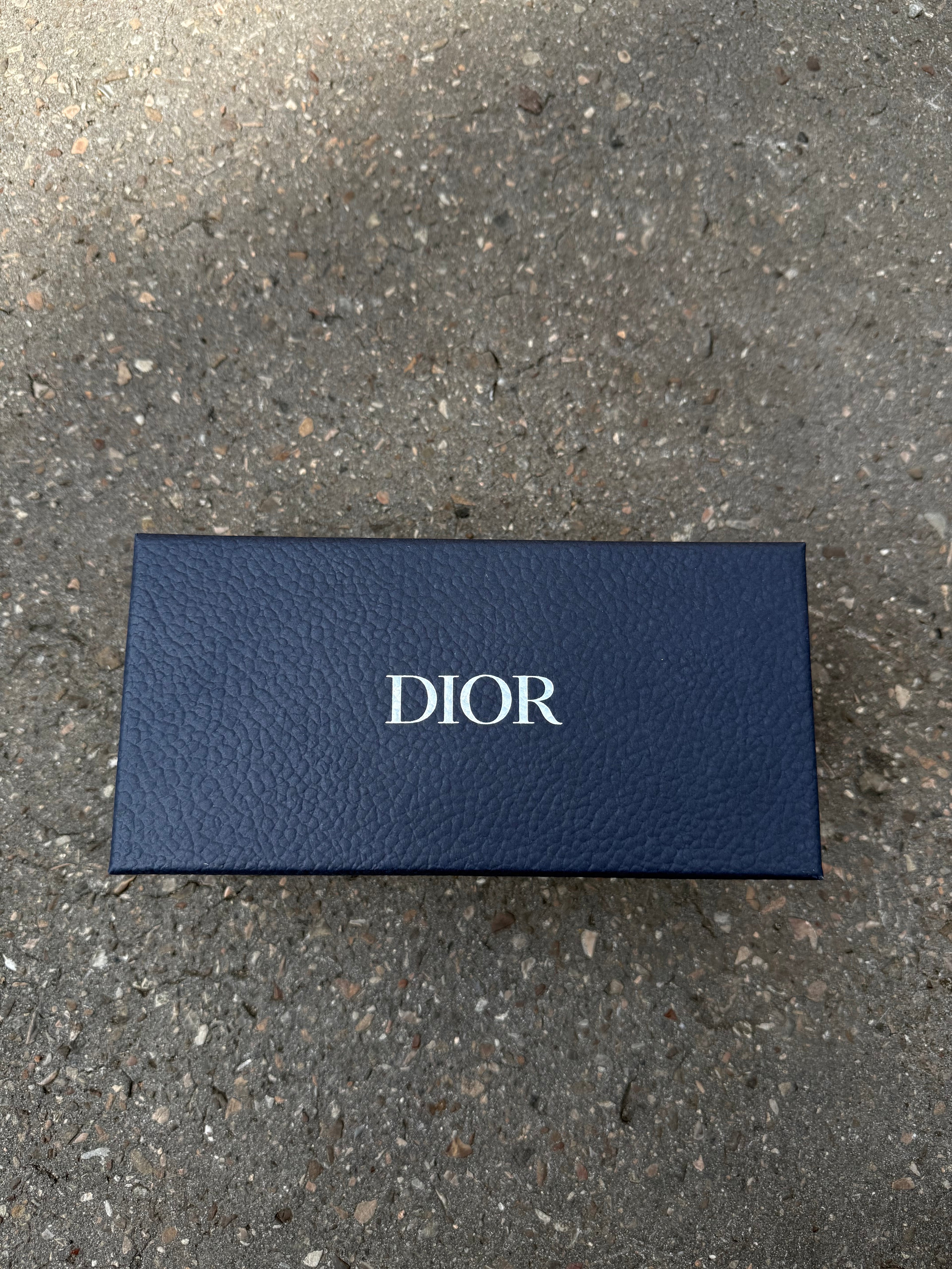 Eine schwarze Sonnenbrille von Dior mit dem Monogram auf den Gläsern und dem Markennamen auf den Bügeln