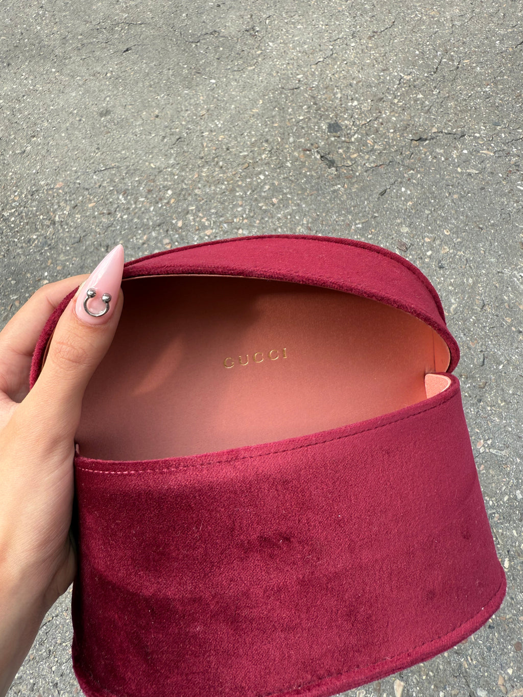 Eine burgunderrote Sonnenbrille von Gucci mit dem Logo in Gold an der Seite und großen quadratischen Gläsern