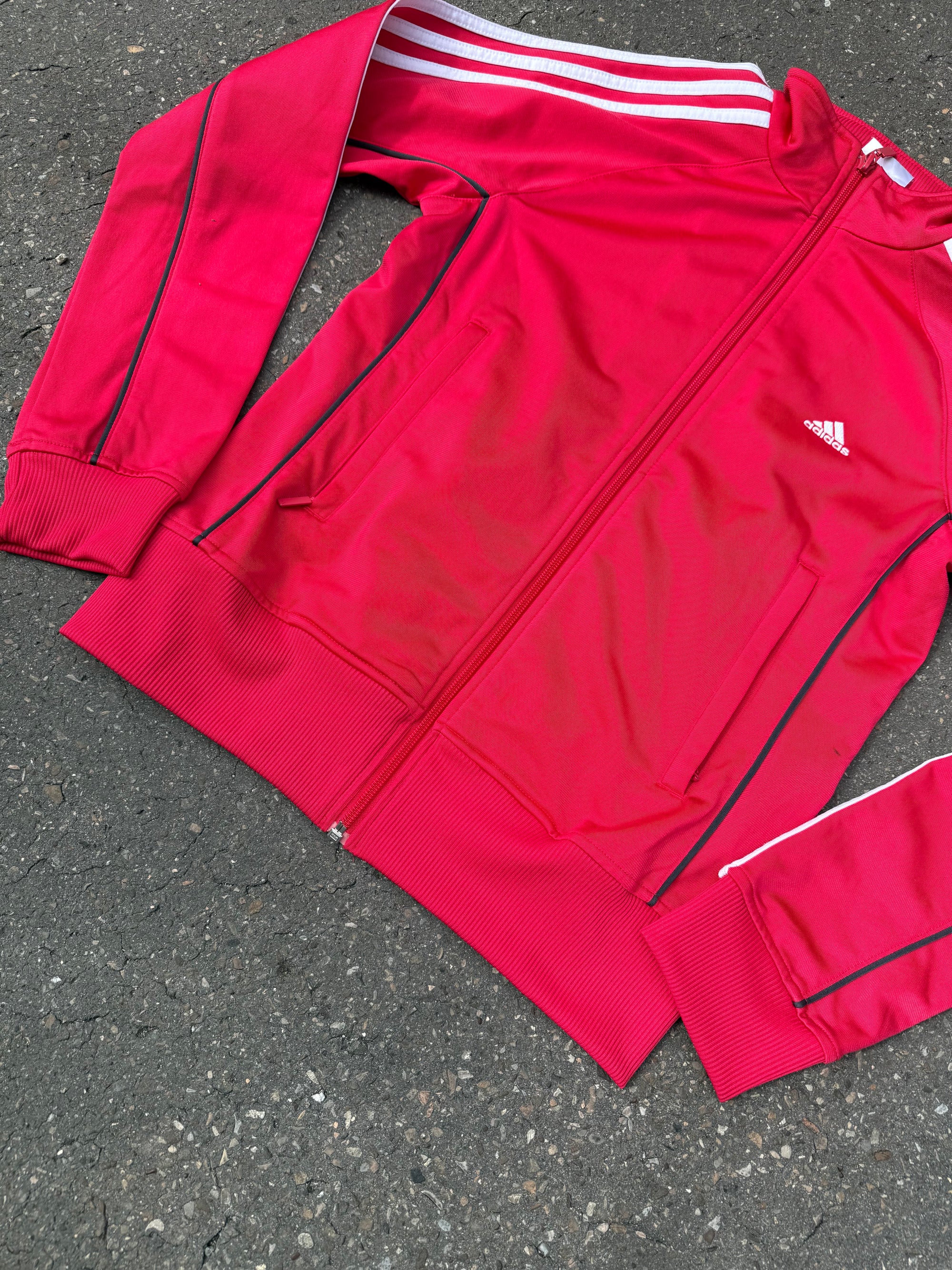 Eine Pinke Trackjacke von Adidas mit weißen Streifen auf den Ärmeln