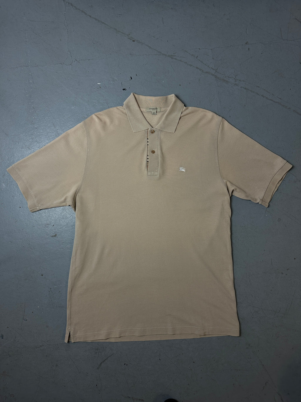 Produktbild von beigenen Burberry Polo auf grauem Boden 