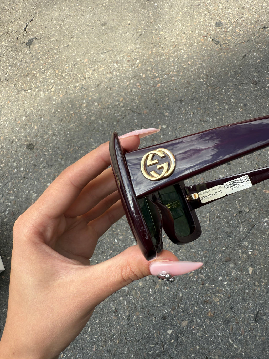 Eine burgunderrote Sonnenbrille von Gucci mit dem Logo in Gold an der Seite und großen quadratischen Gläsern