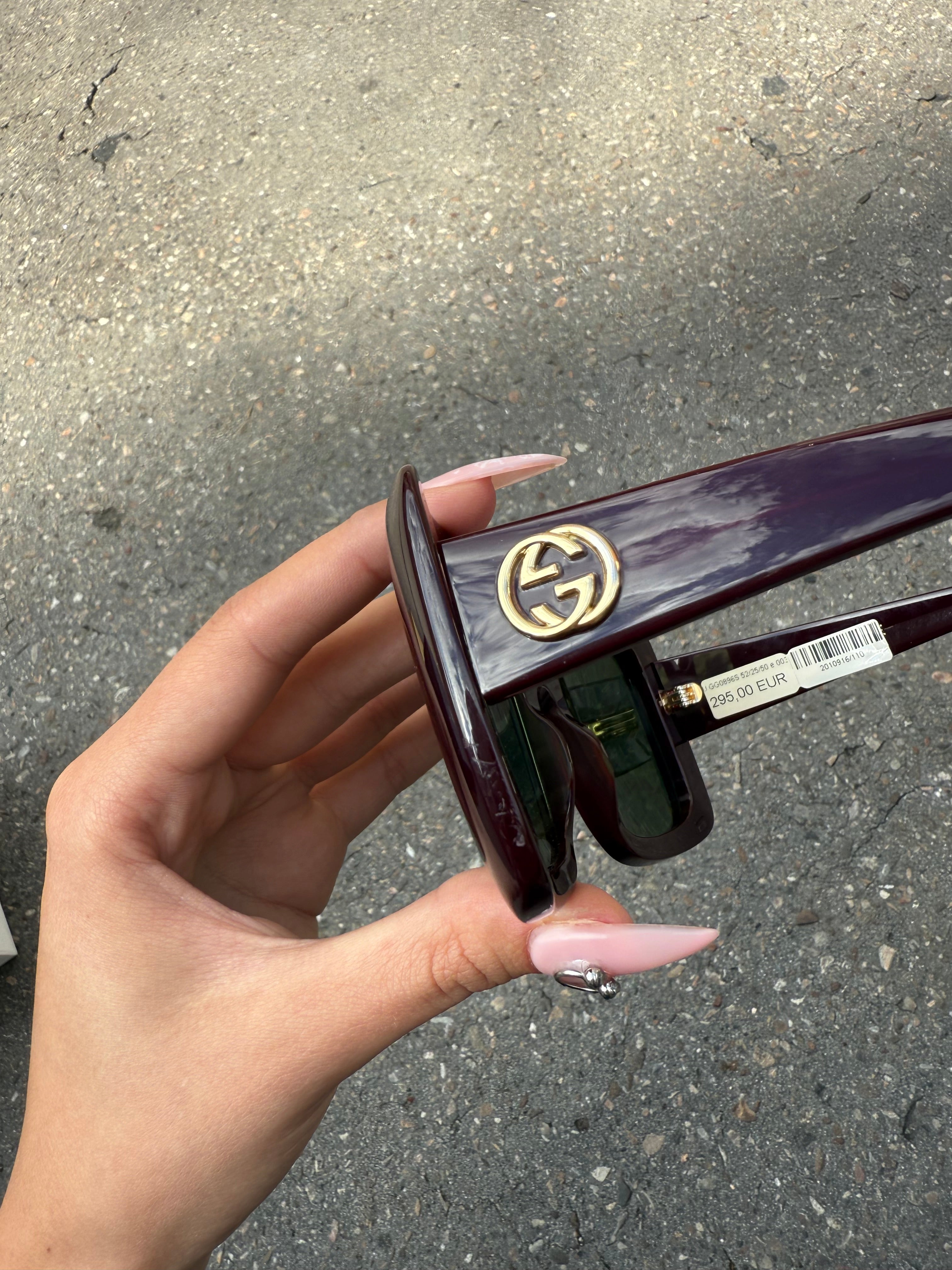 Eine burgunderrote Sonnenbrille von Gucci mit dem Logo in Gold an der Seite und großen quadratischen Gläsern