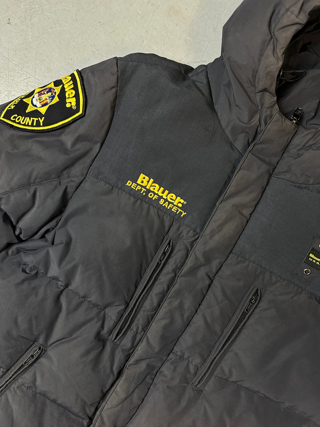 Detailliertes Produktbild von Grauer Blauer Daunen Jacke in L für grauem Boden