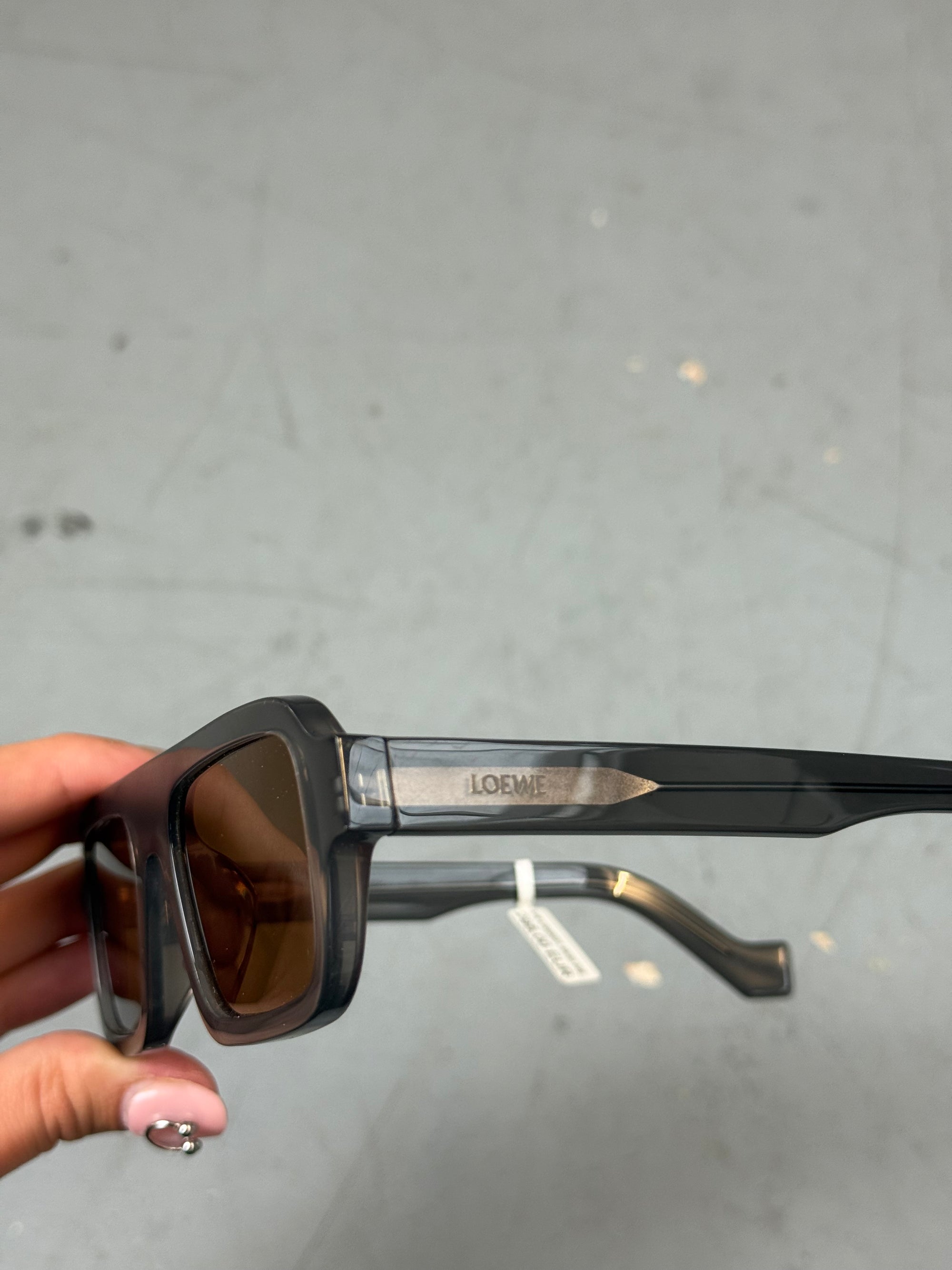 Eine rechteckige Sonnenbrille mit orangen Gläsern und grauem Gestell von Loewe 