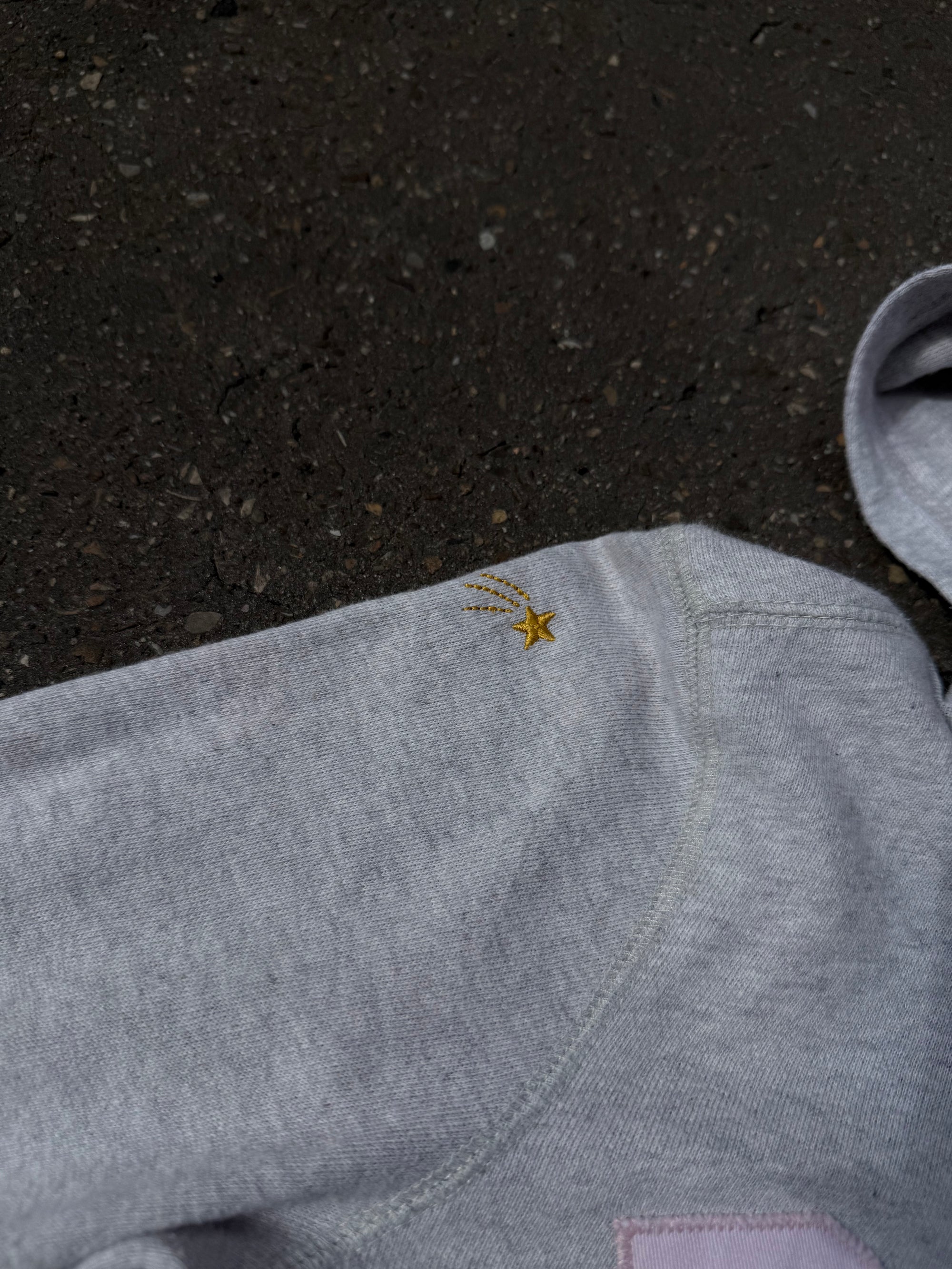 Ein grauer Zip Up Hoodie von Polo Ralph Lauren mit rosa Polo Aufdruck auf der Brust und kleinen patches überall verteilt in XS