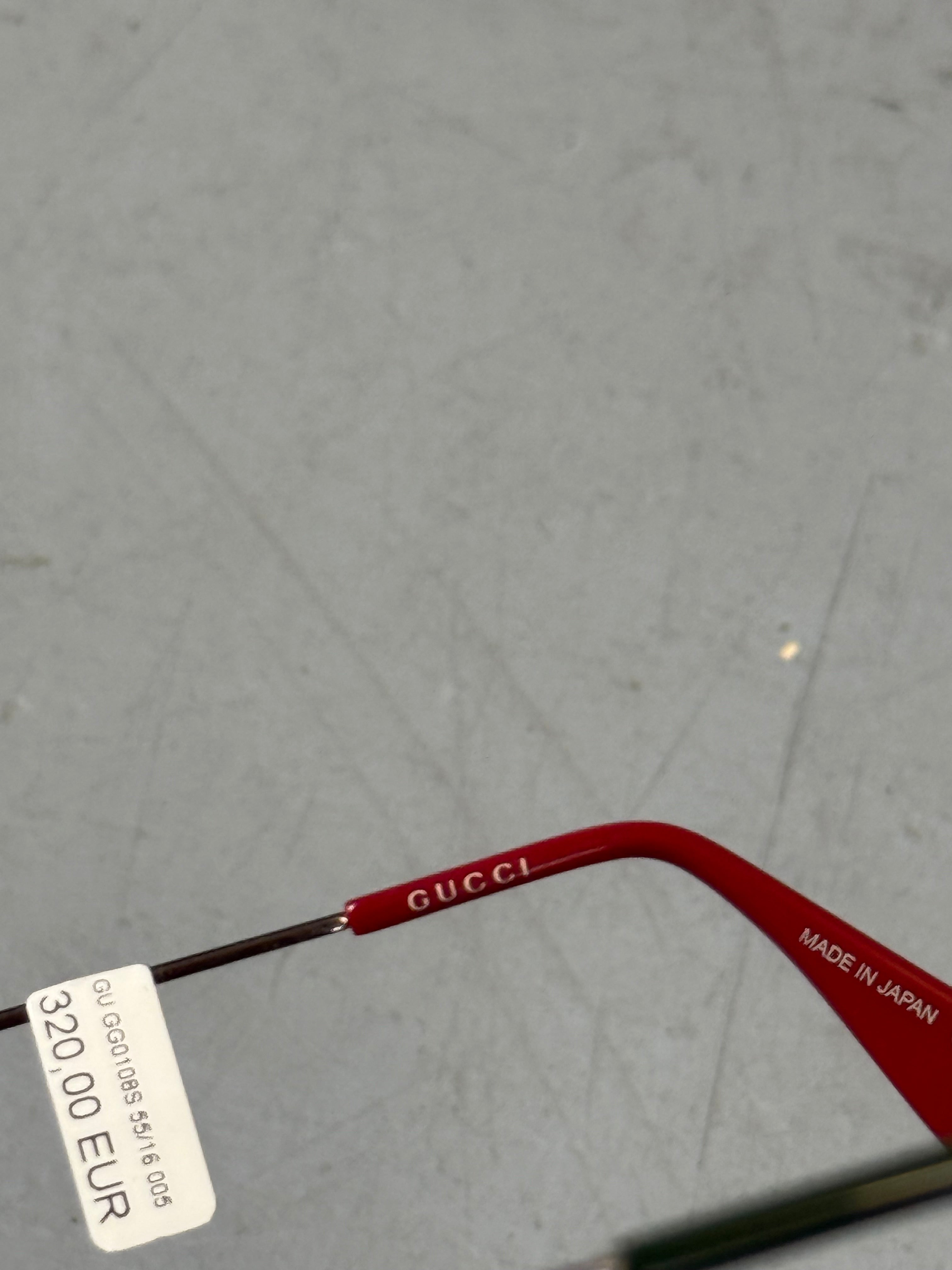 Eine eckige Sonnenbrille von gucci mit dunklen Gläsern und roten und grünen Elementen an den Bügeln 