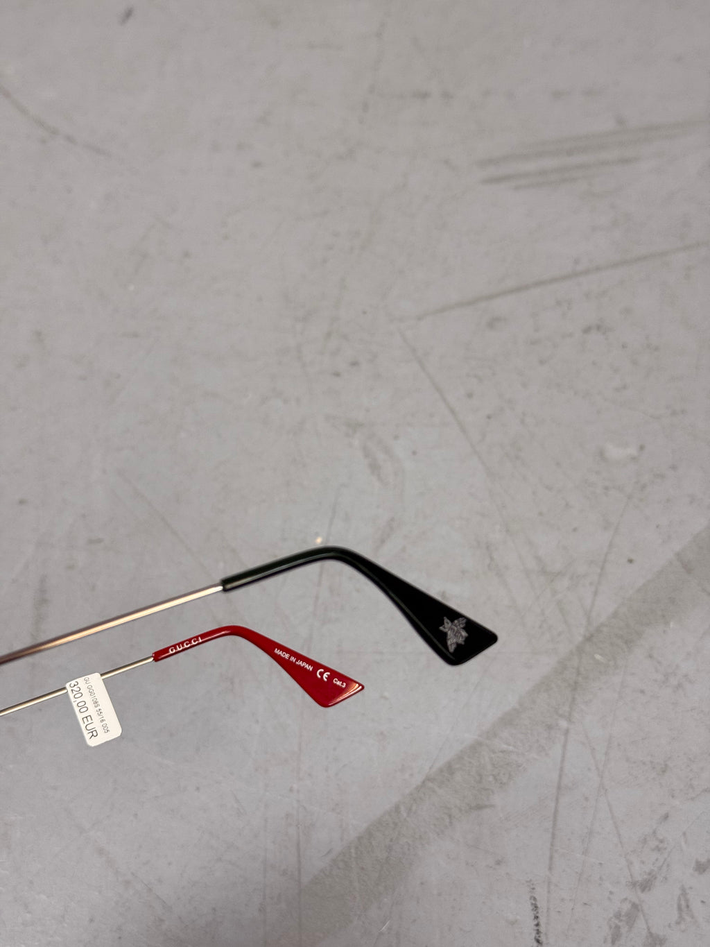 Eine eckige Sonnenbrille von gucci mit dunklen Gläsern und roten und grünen Elementen an den Bügeln 