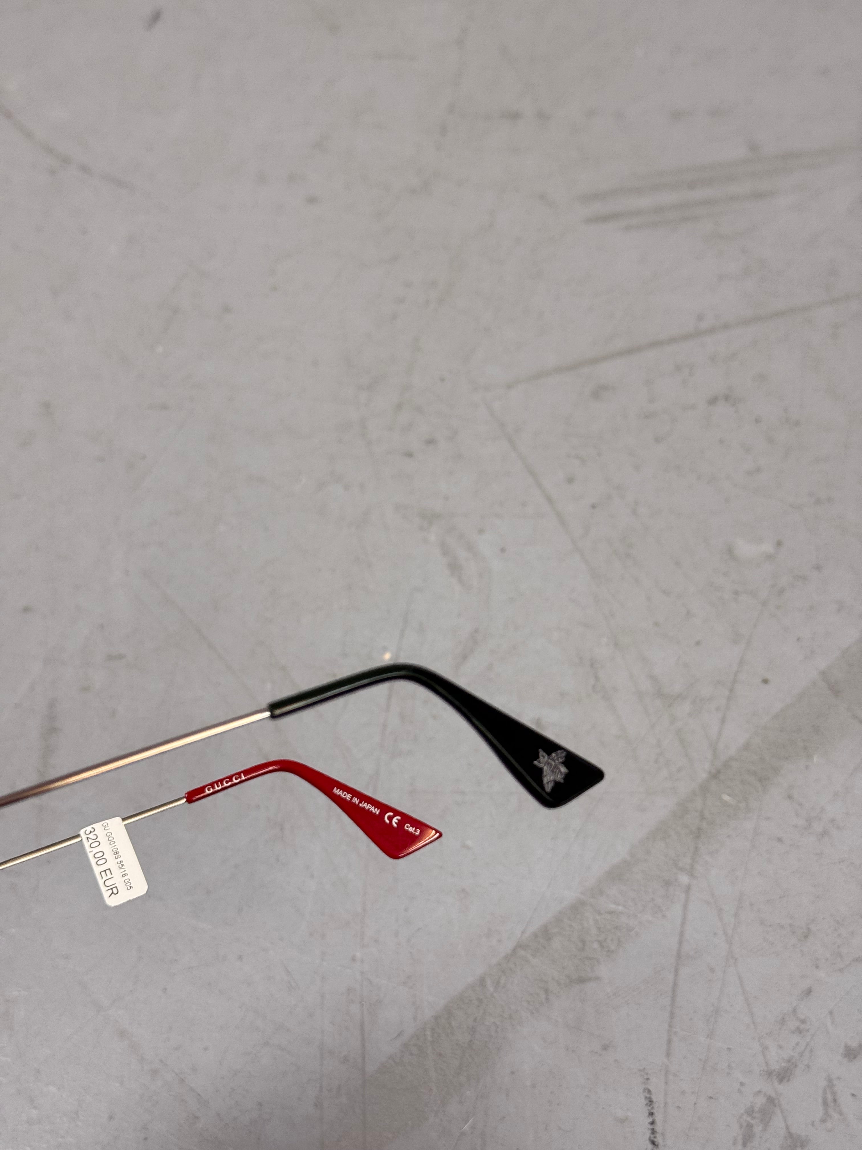 Eine eckige Sonnenbrille von gucci mit dunklen Gläsern und roten und grünen Elementen an den Bügeln 